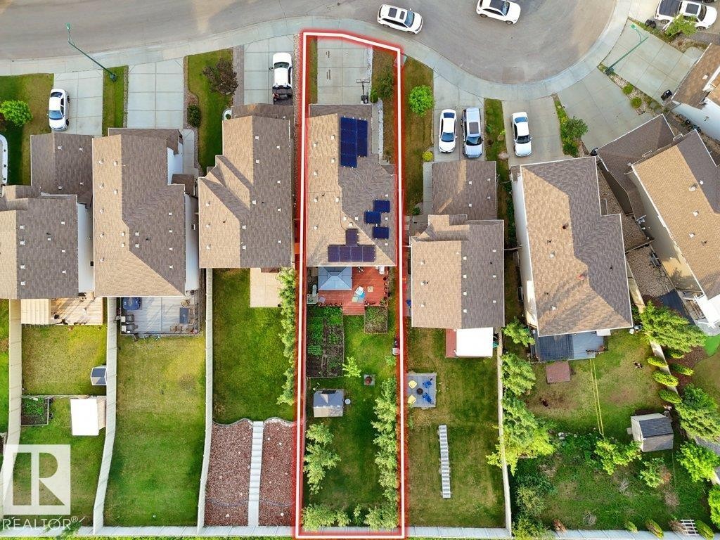 Property featuring a landscaped backyard, a rear deck, a paved driveway, and solar panels on the roof - 3756 8 Street, Edmonton, AB