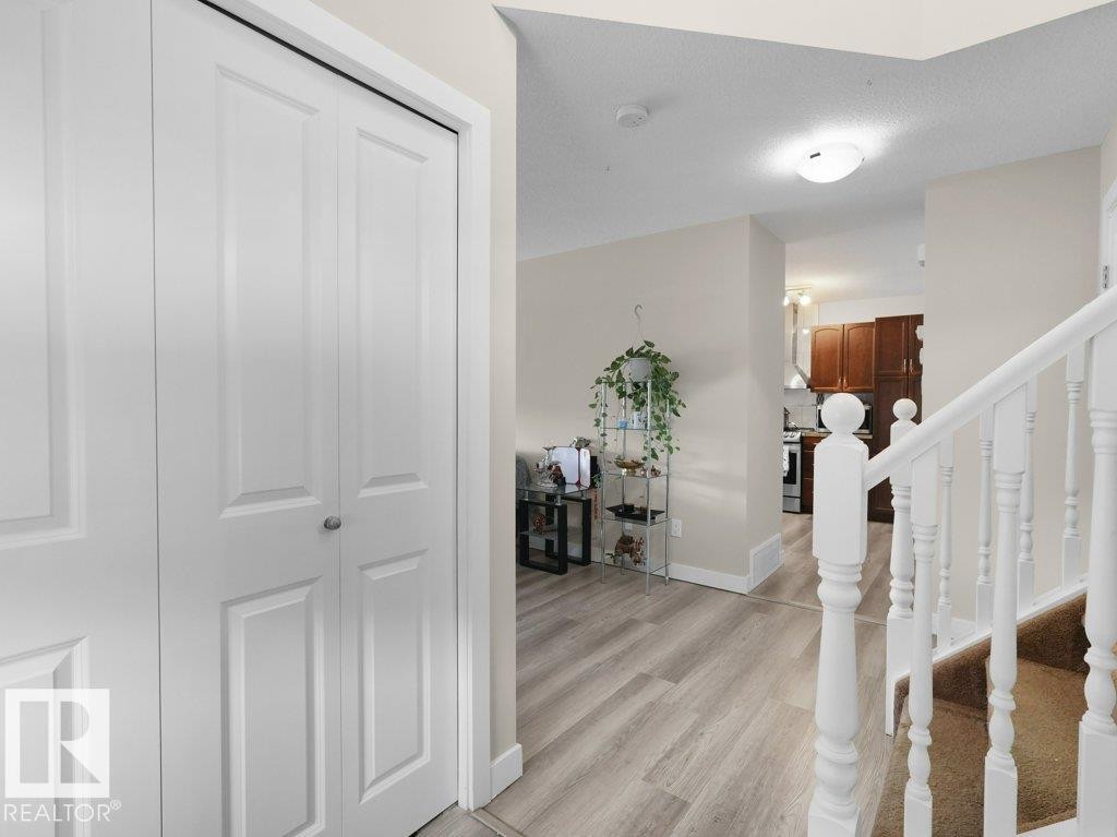 Entryway featuring light wood-finish flooring, white bi-fold closet doors, and painted white balusters - 3756 8 Street, Edmonton, AB