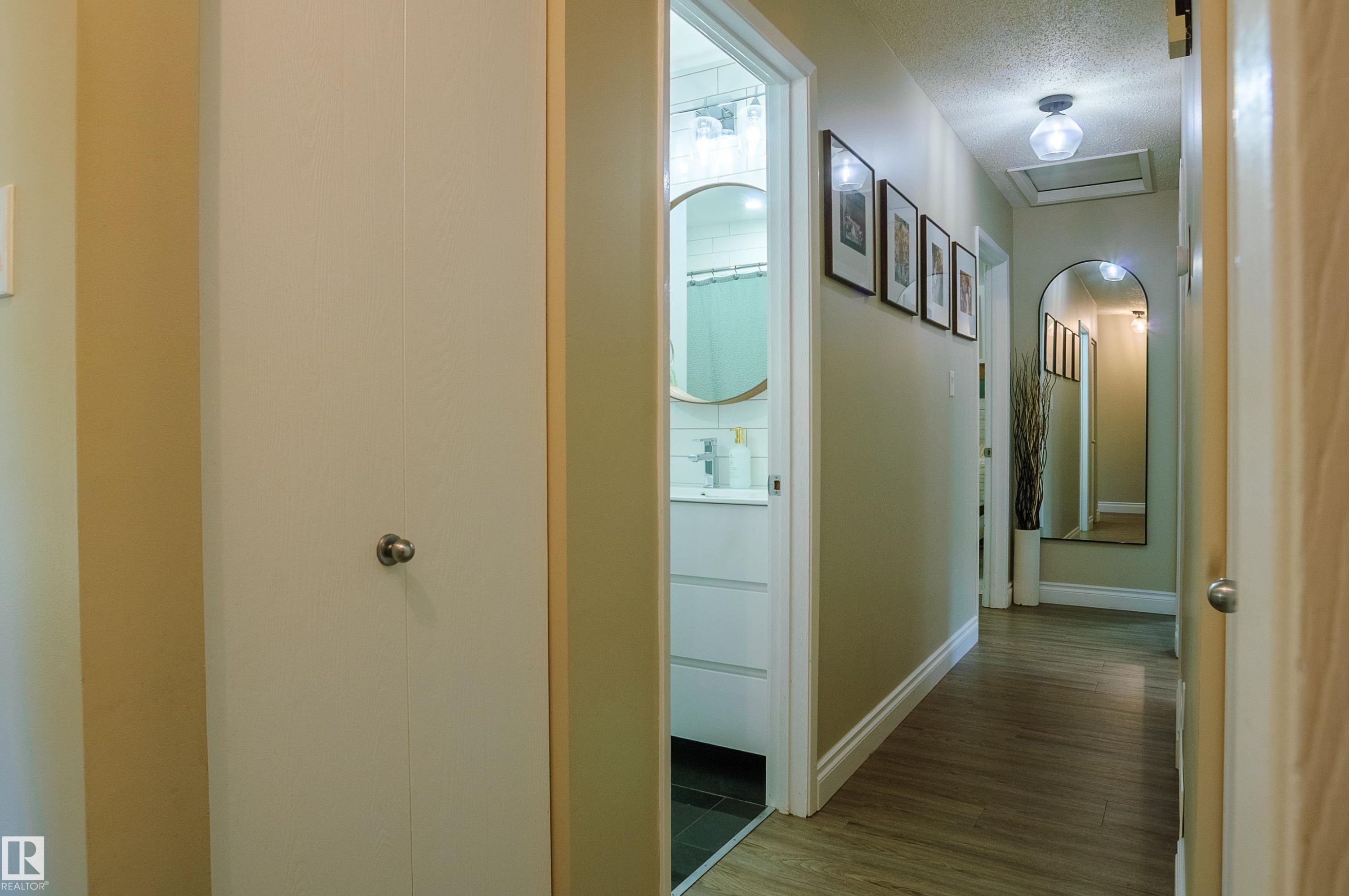 Hallway featuring wood-finish flooring, light tan wall color, a flush-mount ceiling light fixture, and white baseboards - 58 Lodgepole Crescent, St. Albert, AB