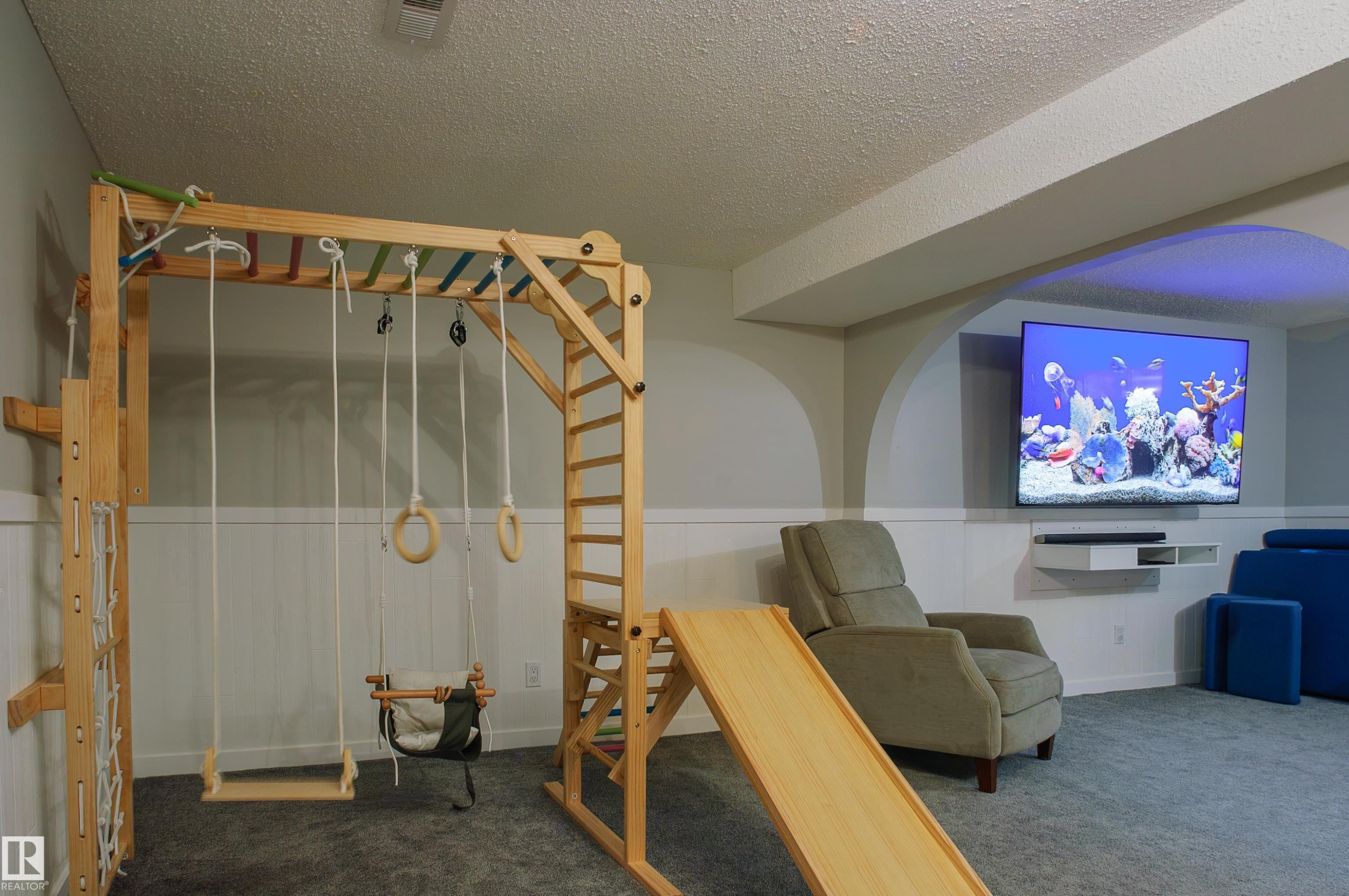 Recreational room featuring a mounted television, built-in shelving, carpet flooring, and wainscoting - 58 Lodgepole Crescent, St. Albert, AB