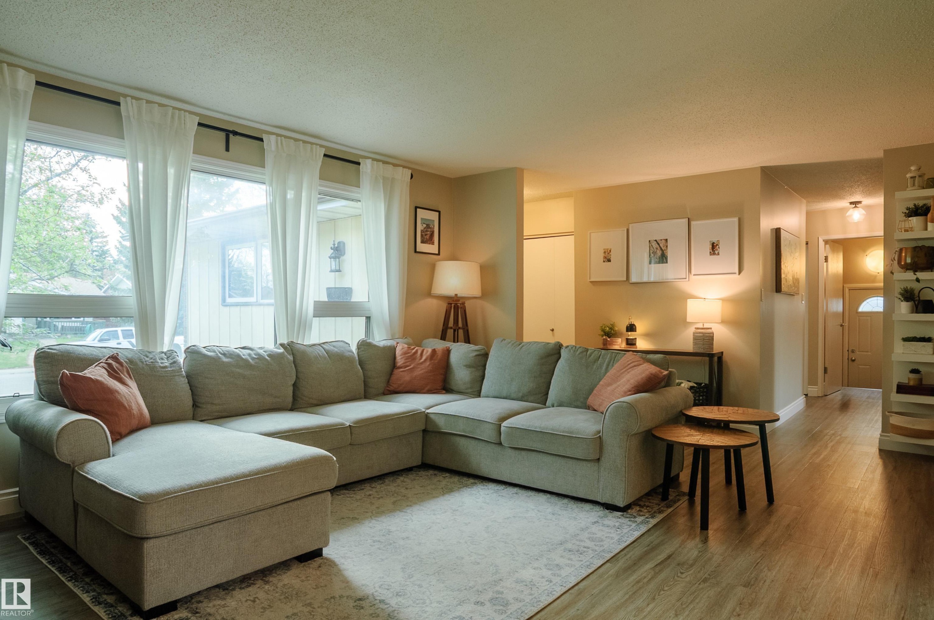 Living area featuring wood-finish flooring, a large window bank, and neutral wall tones - 58 Lodgepole Crescent, St. Albert, AB