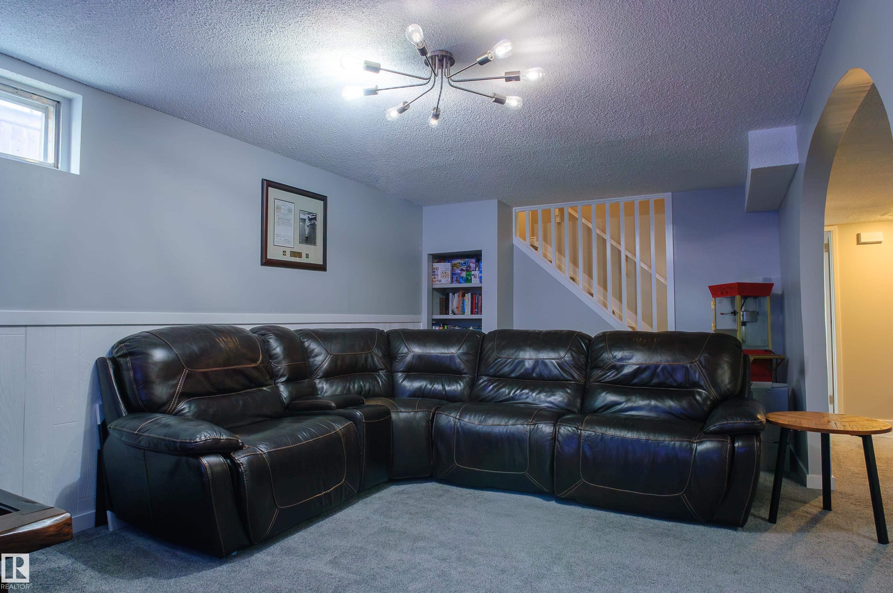 Carpeted room featuring a white paneled wainscoting, light gray walls, an arched entryway, and a contemporary ceiling light fixture - 58 Lodgepole Crescent, St. Albert, AB
