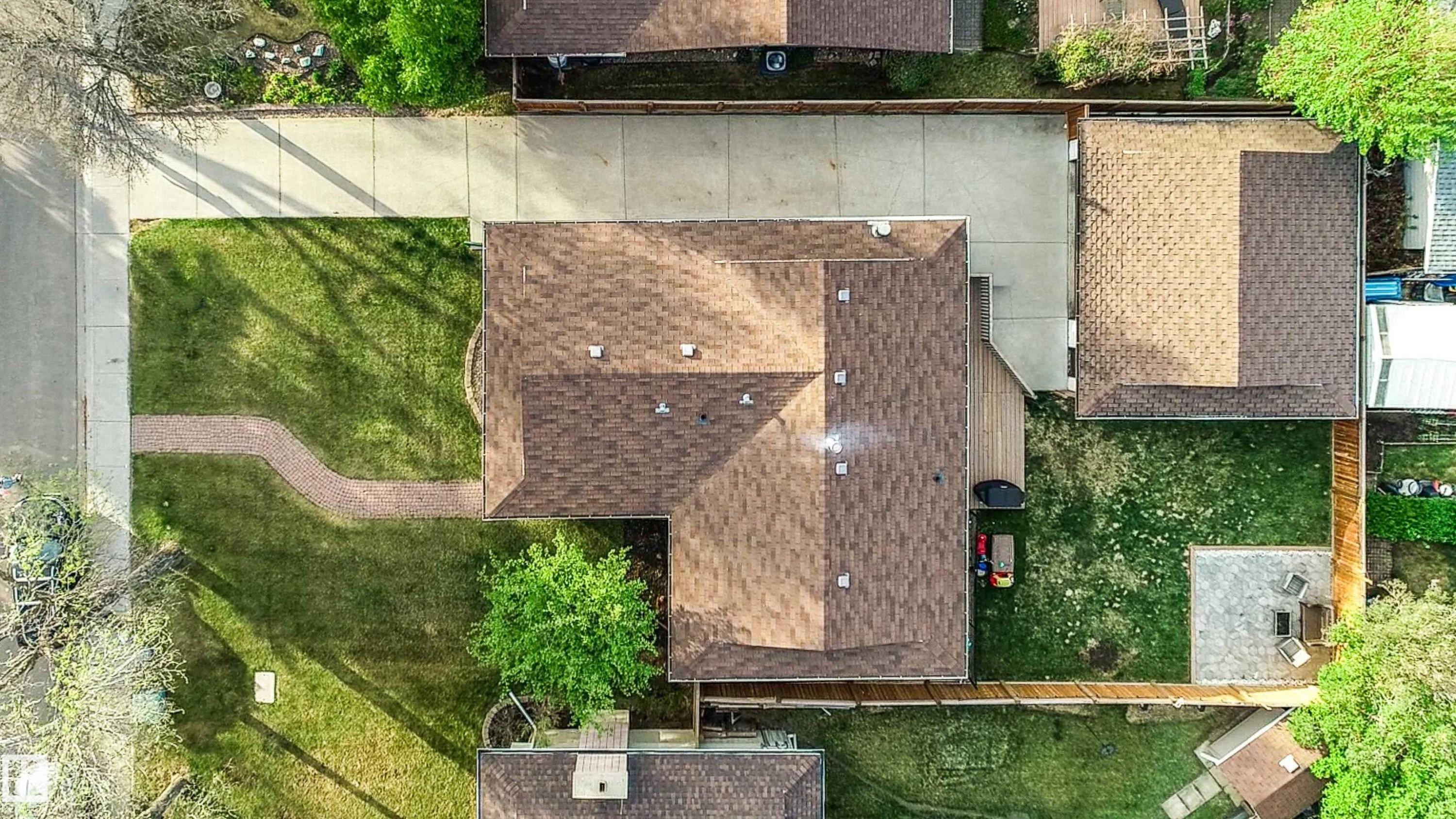 Aerial property overview featuring a brown shingle roof, a generously sized driveway, and a fenced backyard with a patio area - 58 Lodgepole Crescent, St. Albert, AB