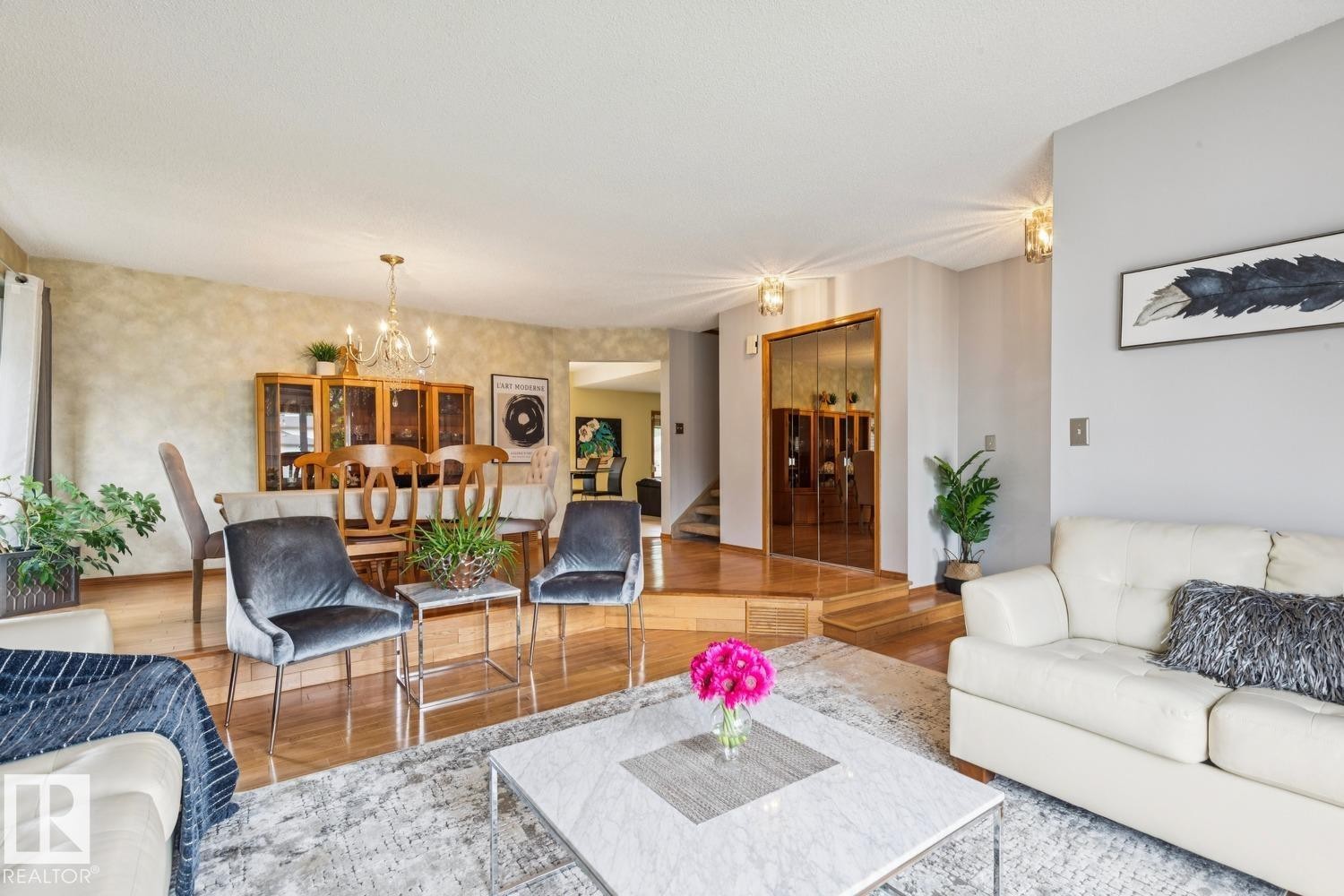 Open-concept living space featuring wood-finish flooring, a dining area with a chandelier, and a recessed entryway with mirrored closet doors - 15804 80 Street, Edmonton, AB