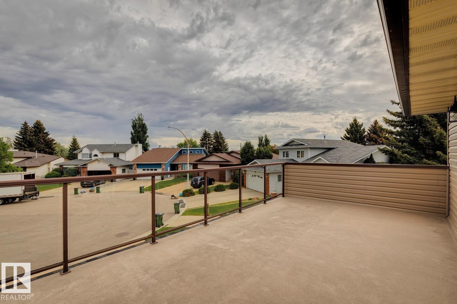 Expansive outdoor balcony featuring a glass panel railing system and durable concrete surface - 15804 80 Street, Edmonton, AB