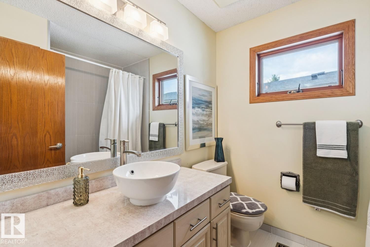 Bathroom featuring a vessel sink, single-handle faucet, stone-finish countertop, and wood-frame window - 15804 80 Street, Edmonton, AB