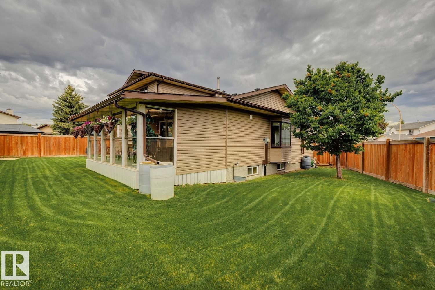 Expansive backyard featuring a manicured lawn, a mature tree, and a full privacy fence - 15804 80 Street, Edmonton, AB