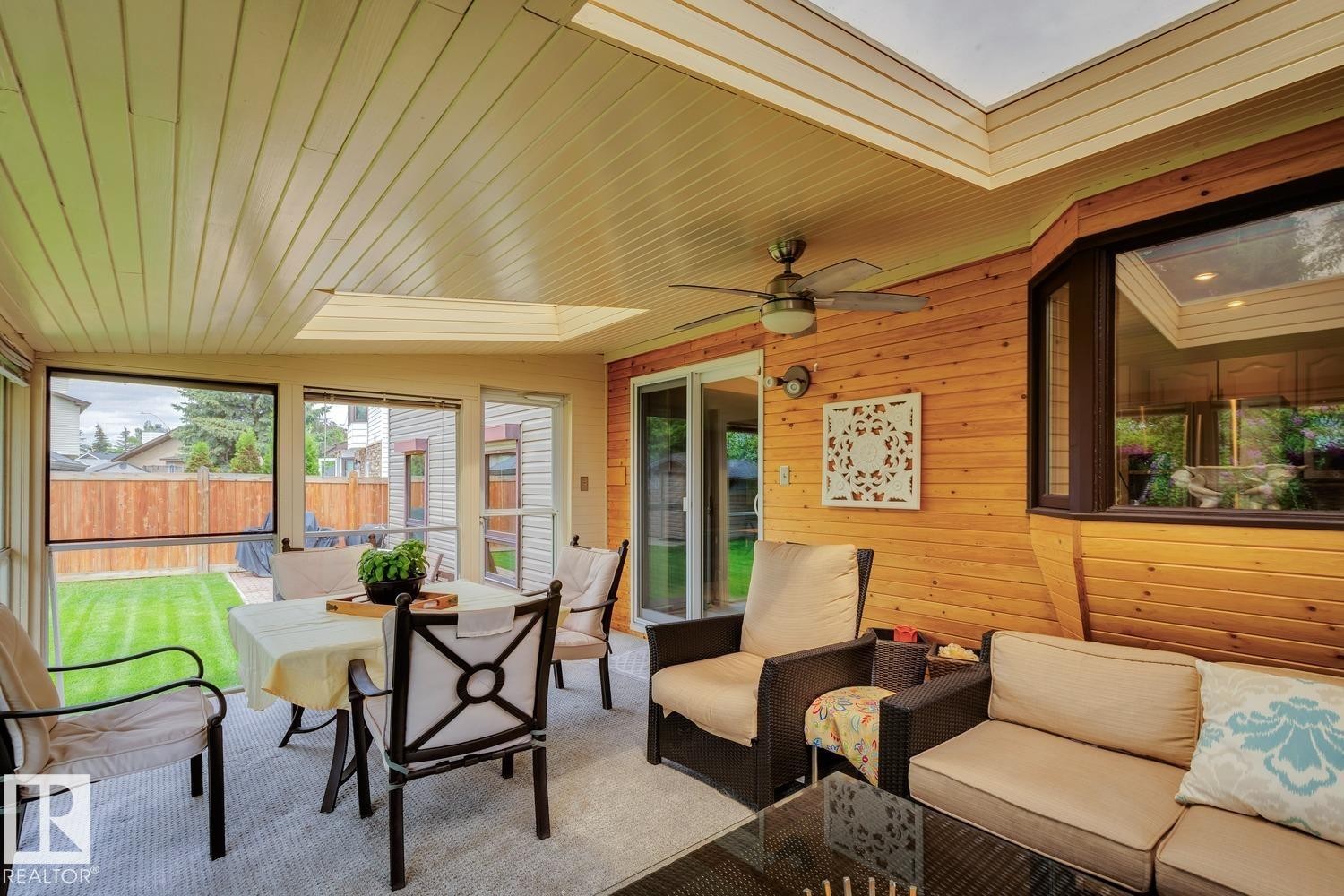Spacious screened-in patio featuring a wood-plank ceiling, skylights, and a ceiling fan - 15804 80 Street, Edmonton, AB