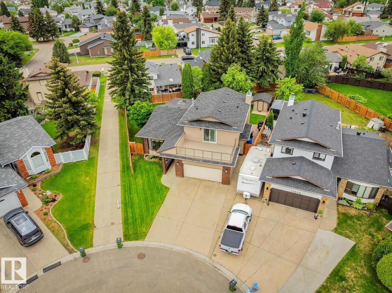 Residential property featuring a two-story home with a tan exterior, dark shingle roof, and an upper-level balcony - 15804 80 Street, Edmonton, AB