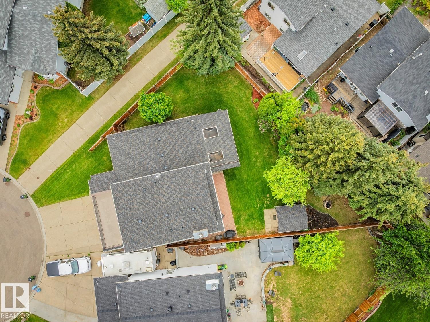 Aerial view showcasing a residential property with a shingled roof, extensive green lawn, mature trees, and concrete driveways - 15804 80 Street, Edmonton, AB