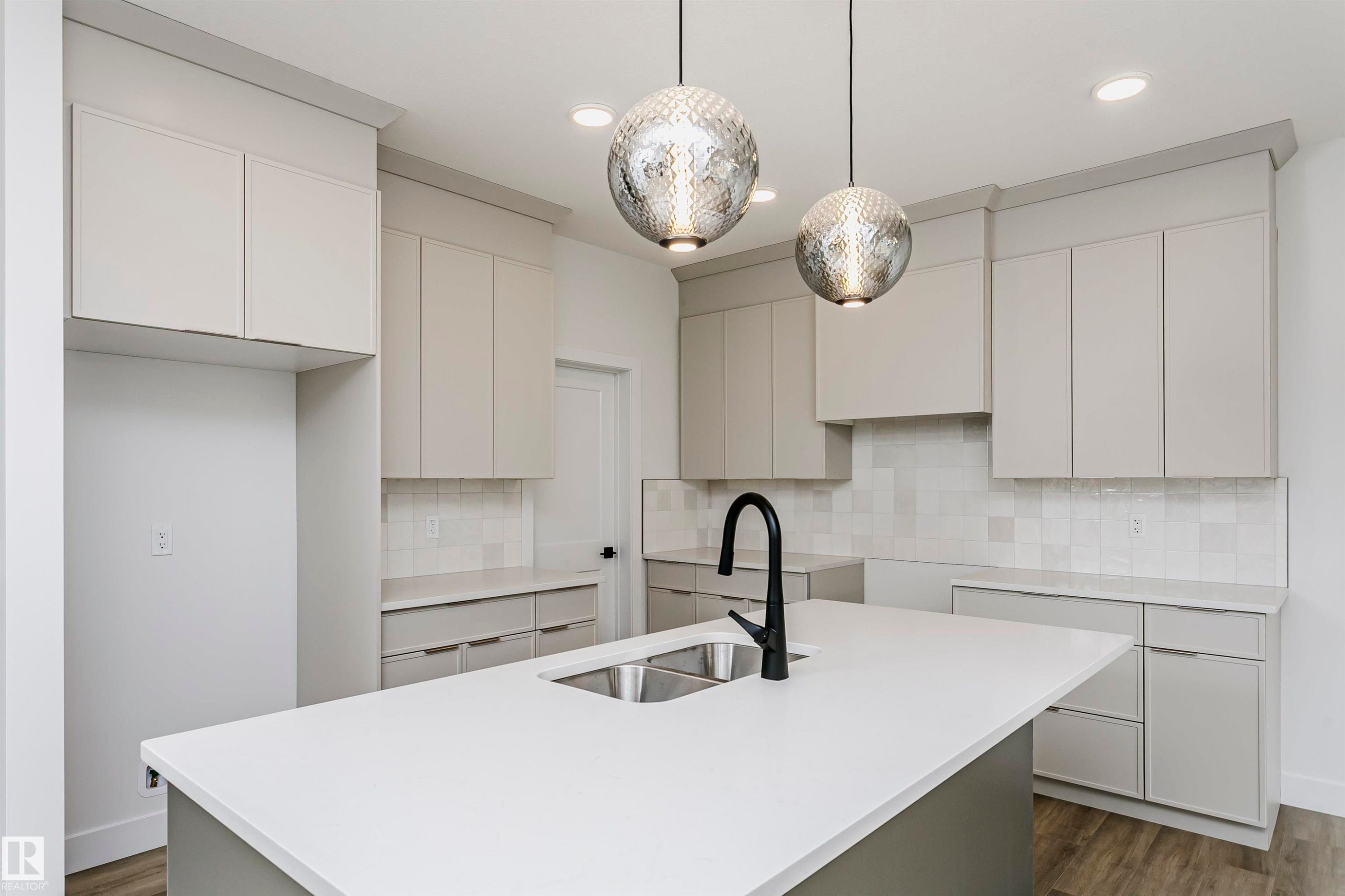 Kitchen featuring a large central island with an undermount double sink and matte black gooseneck faucet - 6210 Dansereau Crescent, Beaumont, AB