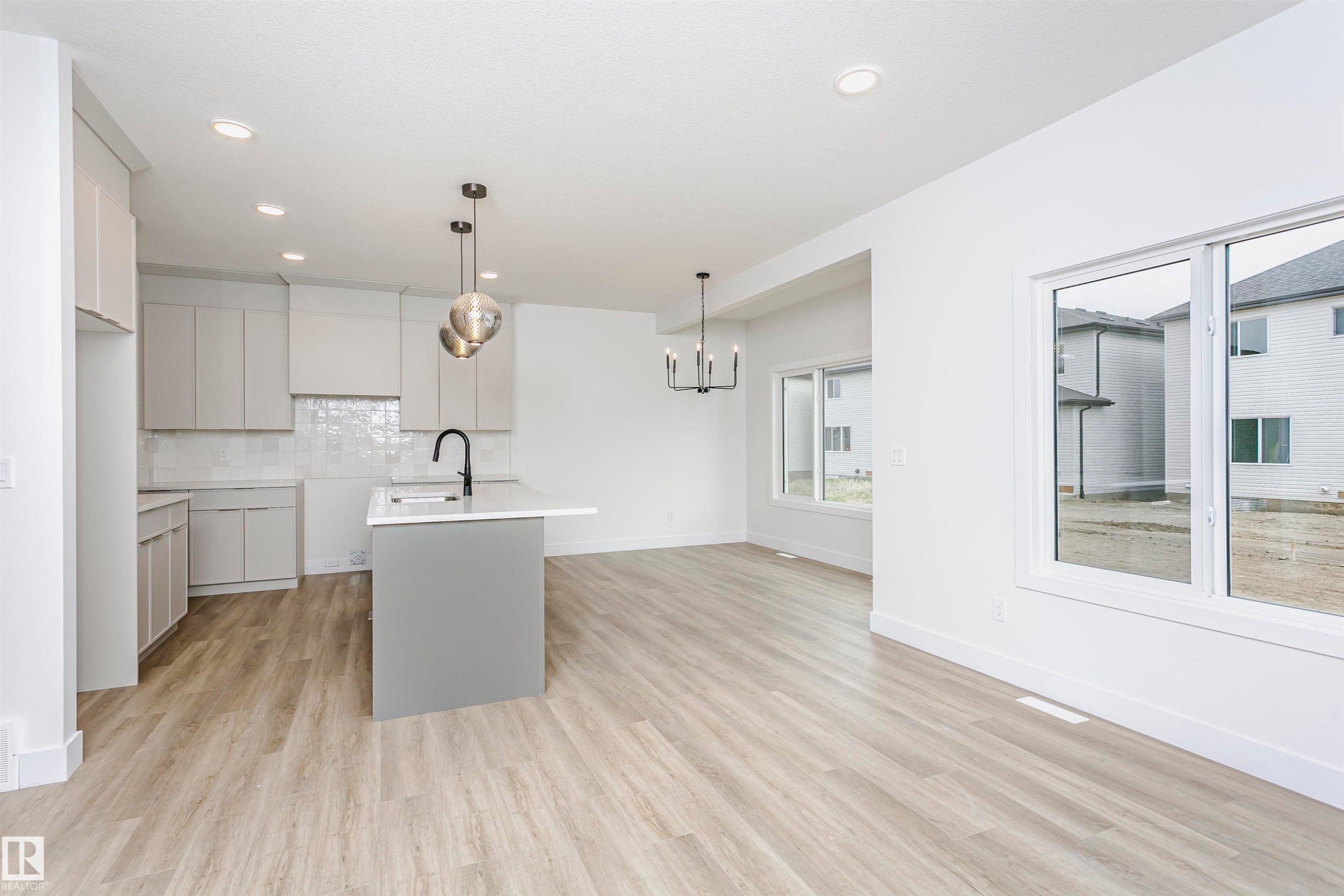 Modern kitchen and living area featuring light wood-finish flooring - 6210 Dansereau Crescent, Beaumont, AB