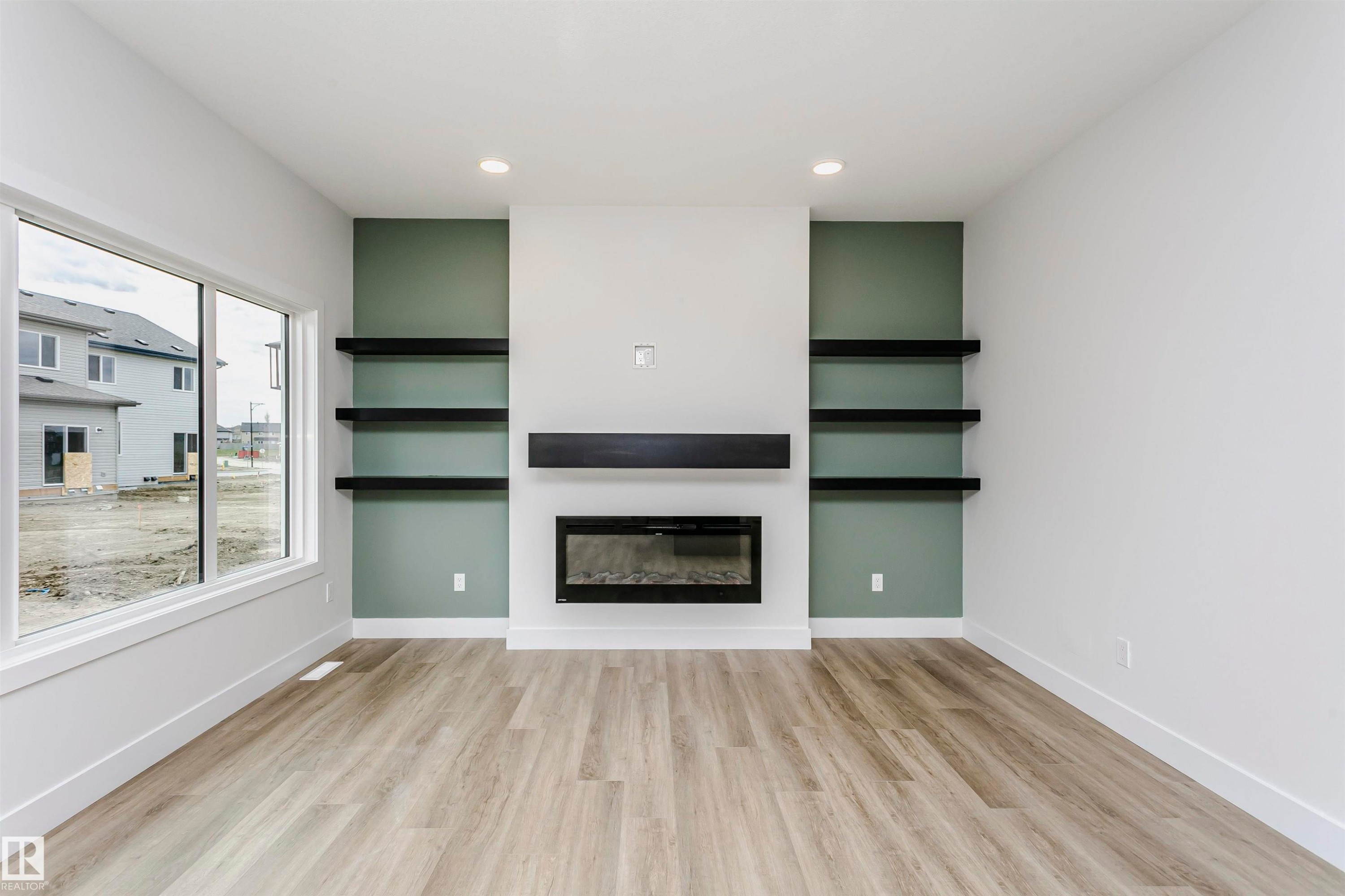 Open-concept living space featuring a contemporary electric fireplace with a dark wood mantel and accent wall - 6210 Dansereau Crescent, Beaumont, AB