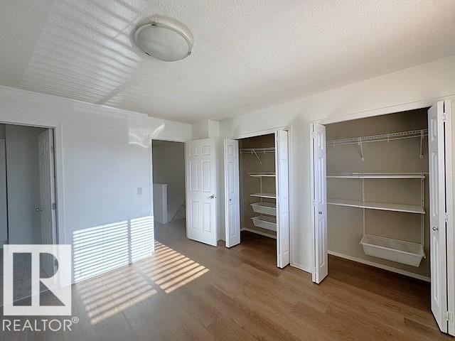 Spacious room featuring wood-finish flooring and a flush-mount ceiling light fixture - #13 3751 12 Street, Edmonton, AB