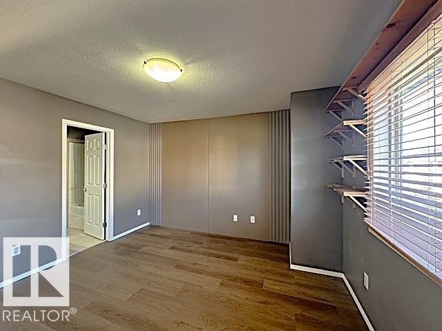 Interior space featuring wood-finish flooring and a flat-panel ceiling light fixture - #13 3751 12 Street, Edmonton, AB