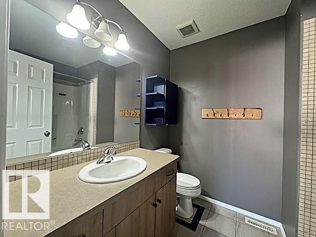 Bathroom vanity featuring an integrated sink, laminate countertop, and wood-finish cabinetry - #13 3751 12 Street, Edmonton, AB
