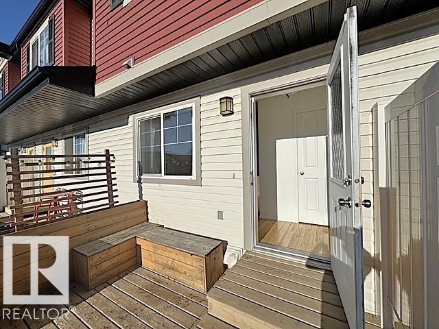 Deck area featuring built-in wooden bench seating, slatted privacy screen, and exterior wall sconce lighting - #13 3751 12 Street, Edmonton, AB