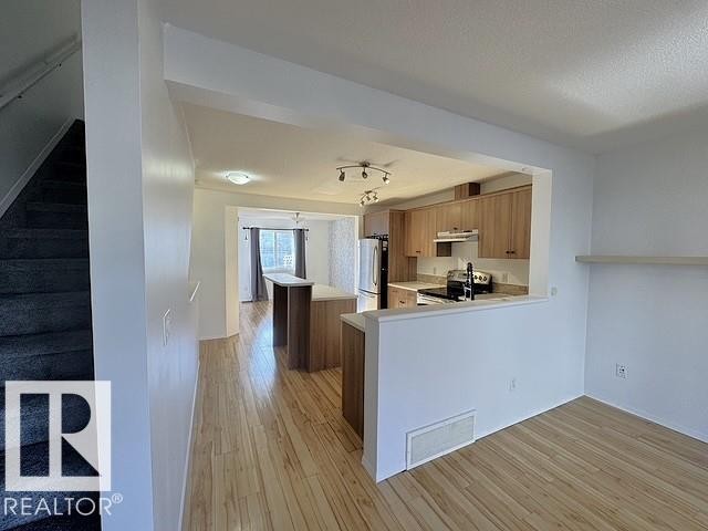 Open-concept living area with wood-finish flooring extending into the kitchen - #13 3751 12 Street, Edmonton, AB