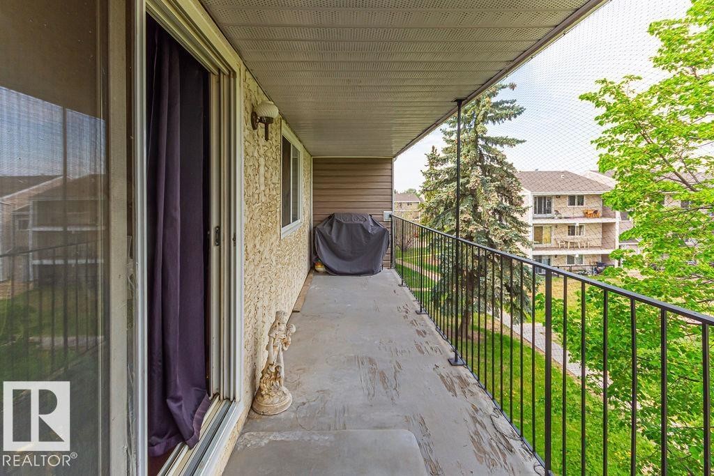 Private balcony featuring concrete flooring, black metal railing, and an exterior wall light fixture - 6 3819 76 Street, Edmonton, AB