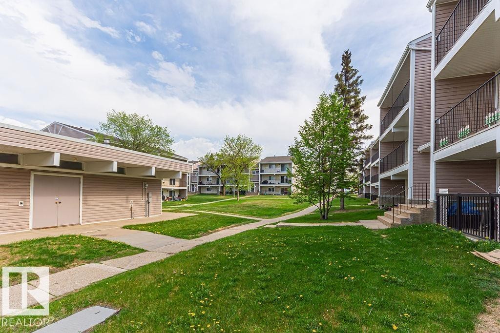 Exterior grounds featuring multiple buildings, manicured lawns, and concrete pathways - 6 3819 76 Street, Edmonton, AB