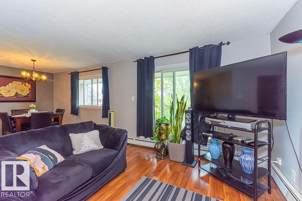 Living space featuring wood-finish flooring and a dining area with an overhead chandelier - 6 3819 76 Street, Edmonton, AB