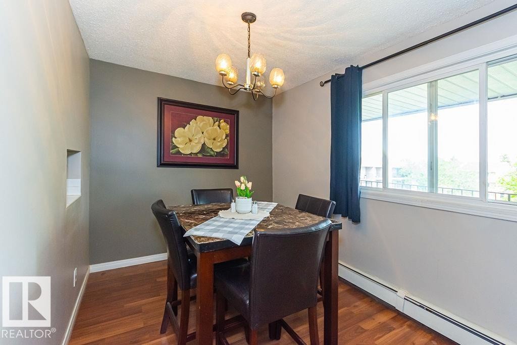 Dining area featuring wood-finish flooring, a multi-pane window, and a built-in wall niche - 6 3819 76 Street, Edmonton, AB