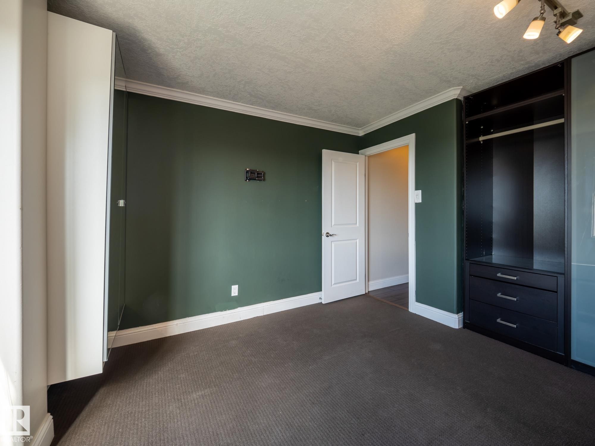 Room featuring dark green painted walls, white crown molding, and white baseboards - #Ph4 9725 106 St Nw, Edmonton, AB - Indoor Photo Showing Other Room