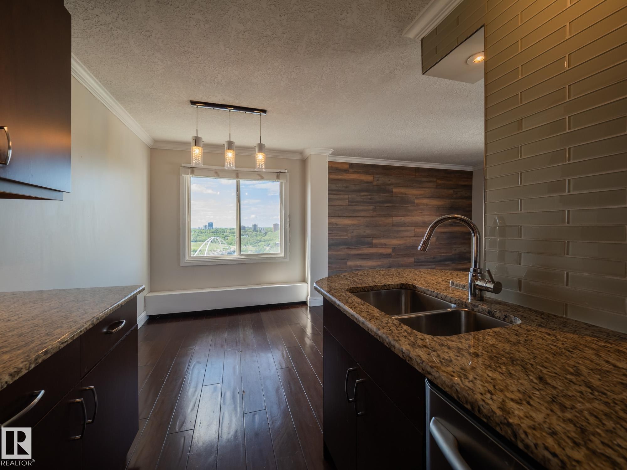 Kitchen featuring granite countertops, a double stainless steel sink with a gooseneck faucet, and a subway tile backsplash - #Ph4 9725 106 St Nw, Edmonton, AB - Indoor Photo Showing Kitchen With Double Sink