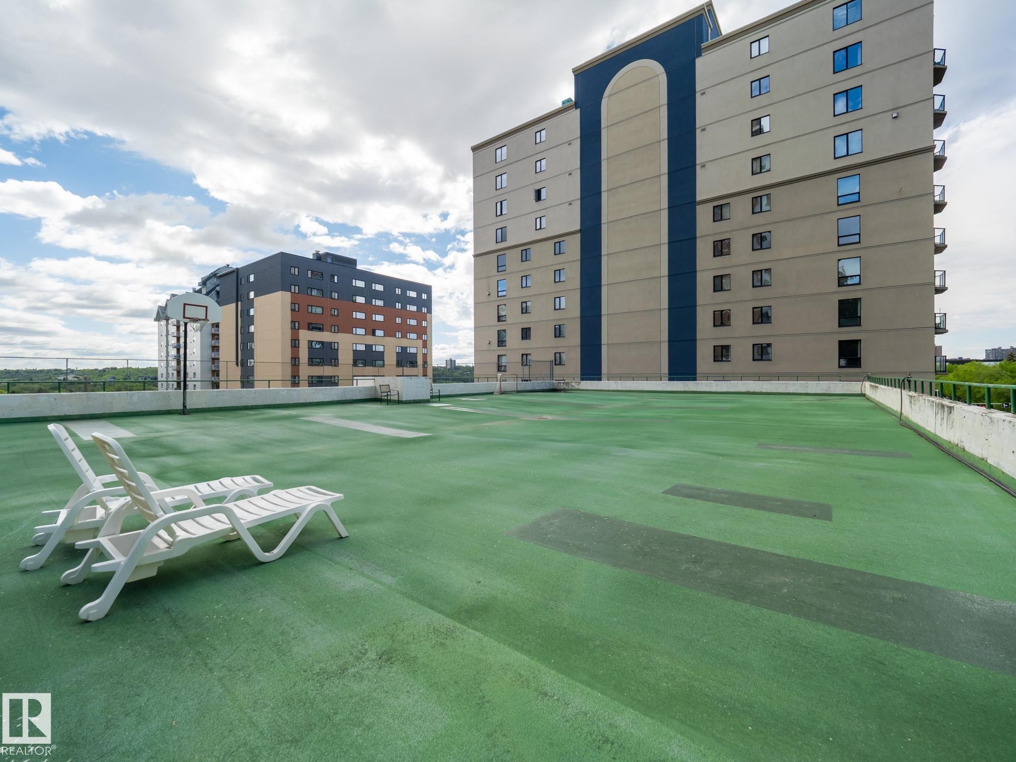 Rooftop recreation area featuring a green-toned surface, perimeter fencing, and a basketball hoop - #Ph4 9725 106 St Nw, Edmonton, AB - Outdoor