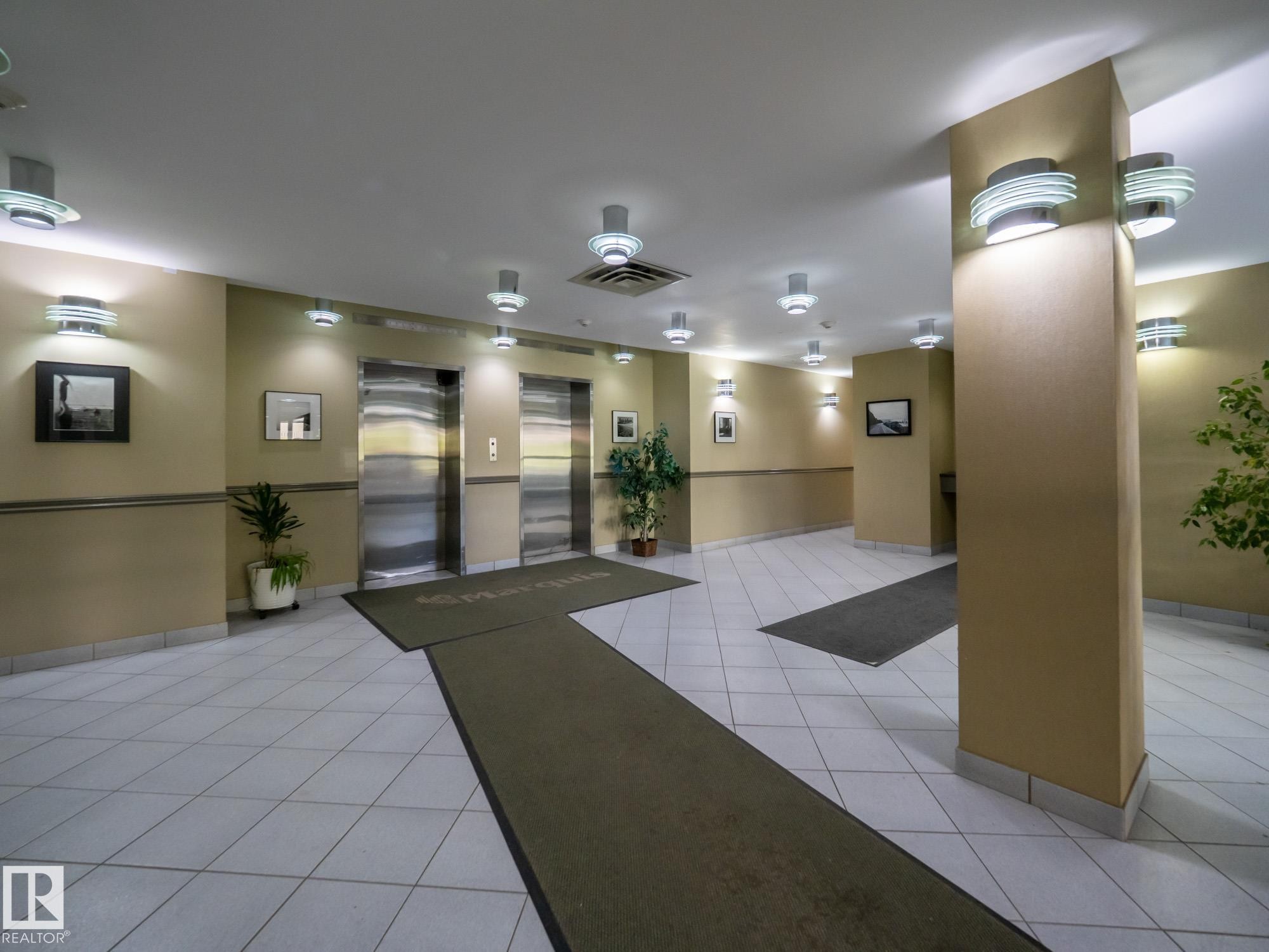 Lobby area featuring two brushed stainless steel elevators, recessed ceiling lighting, wall sconces, and light-toned tile flooring - #Ph4 9725 106 St Nw, Edmonton, AB - Indoor Photo Showing Other Room