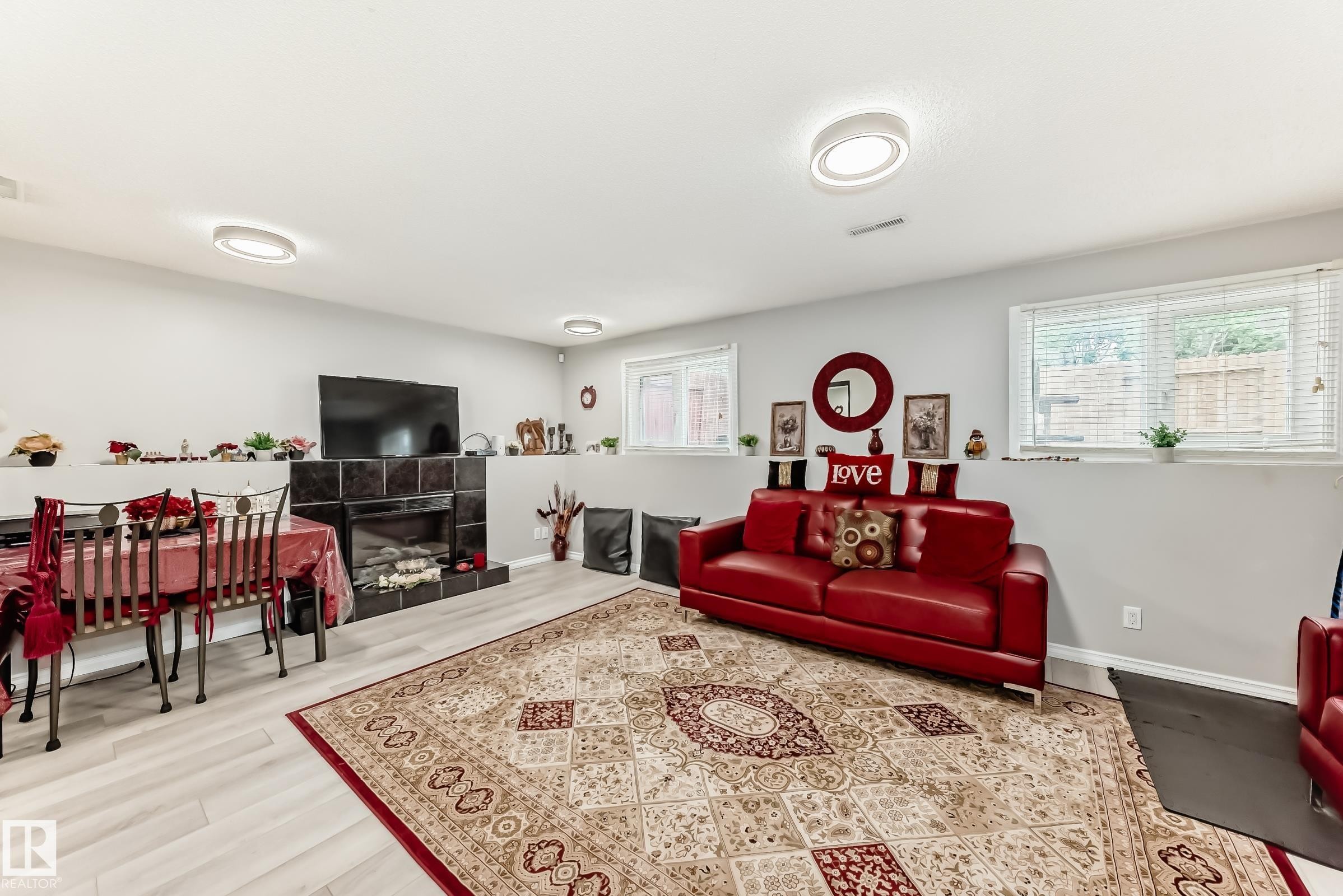 Spacious interior featuring light wood-finish flooring, a tiled fireplace, and multiple windows providing natural light - 3843 47 Street Nw, Edmonton, AB - Indoor Photo Showing Living Room