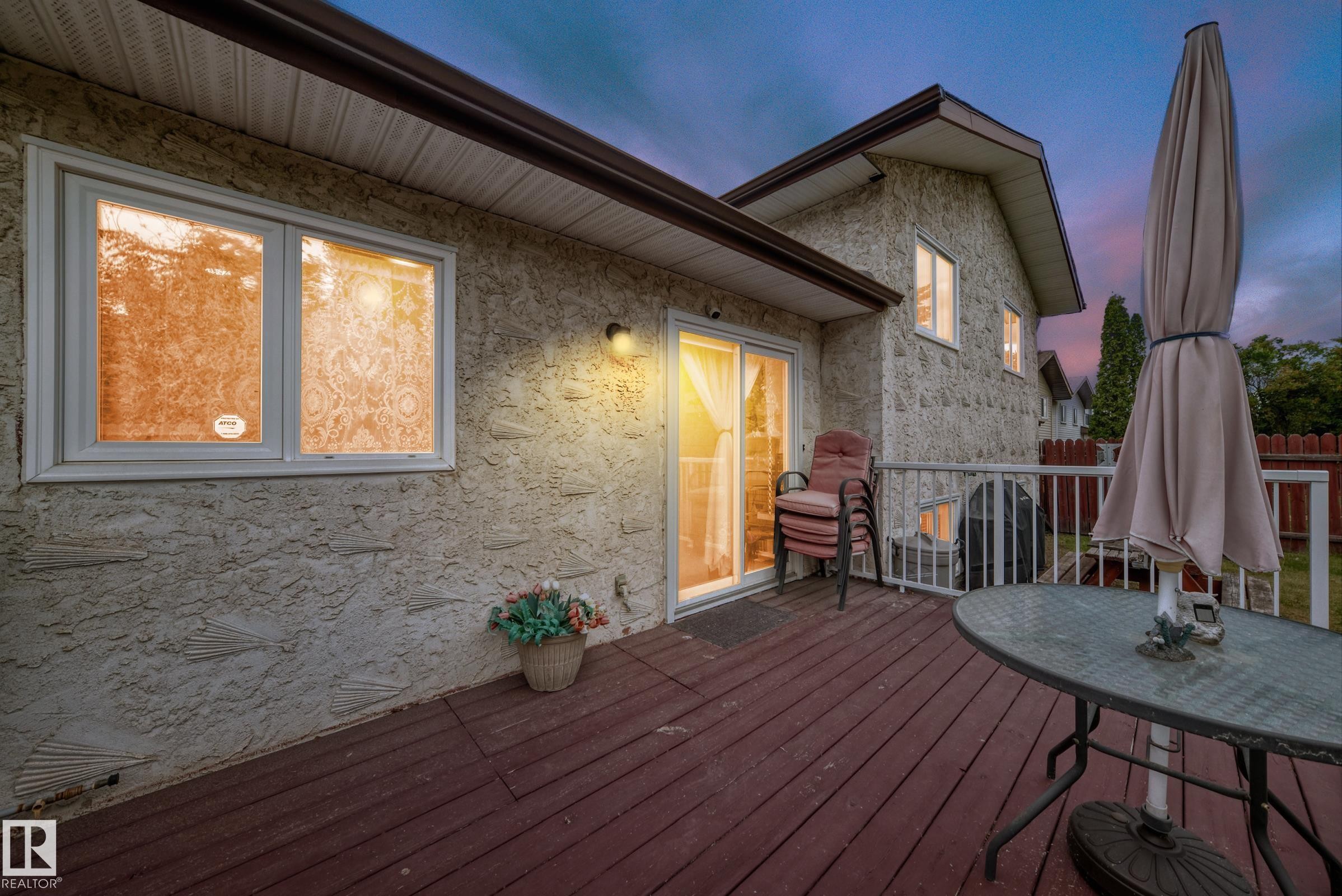 Expansive wood-finish deck with white railing, featuring sliding glass door access to the interior - 3843 47 Street Nw, Edmonton, AB - Outdoor With Deck Patio Veranda With Exterior