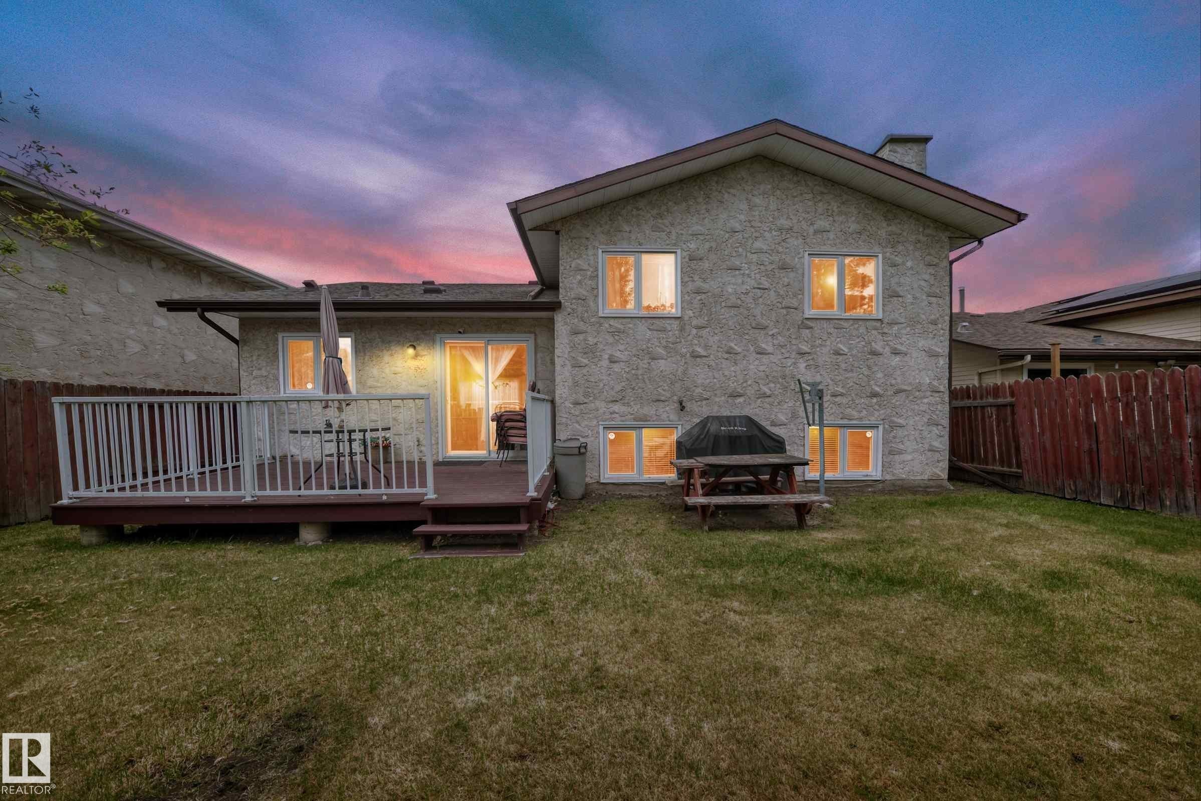Rear exterior with a stone-finish facade and a wood deck - 3843 47 Street Nw, Edmonton, AB - Outdoor With Deck Patio Veranda
