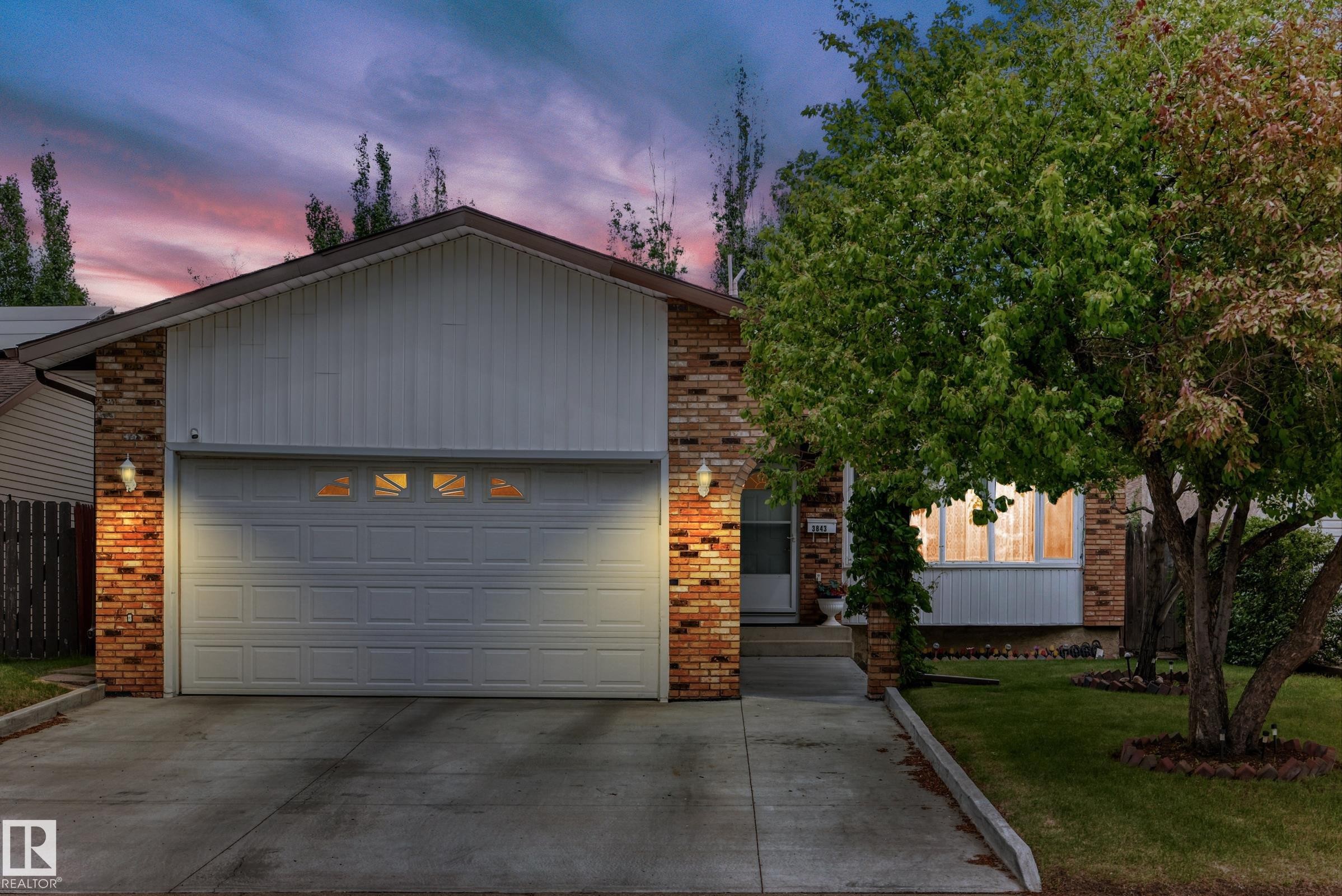 Brick and siding exterior with a concrete driveway and an attached garage featuring window inserts - 3843 47 Street Nw, Edmonton, AB - Outdoor