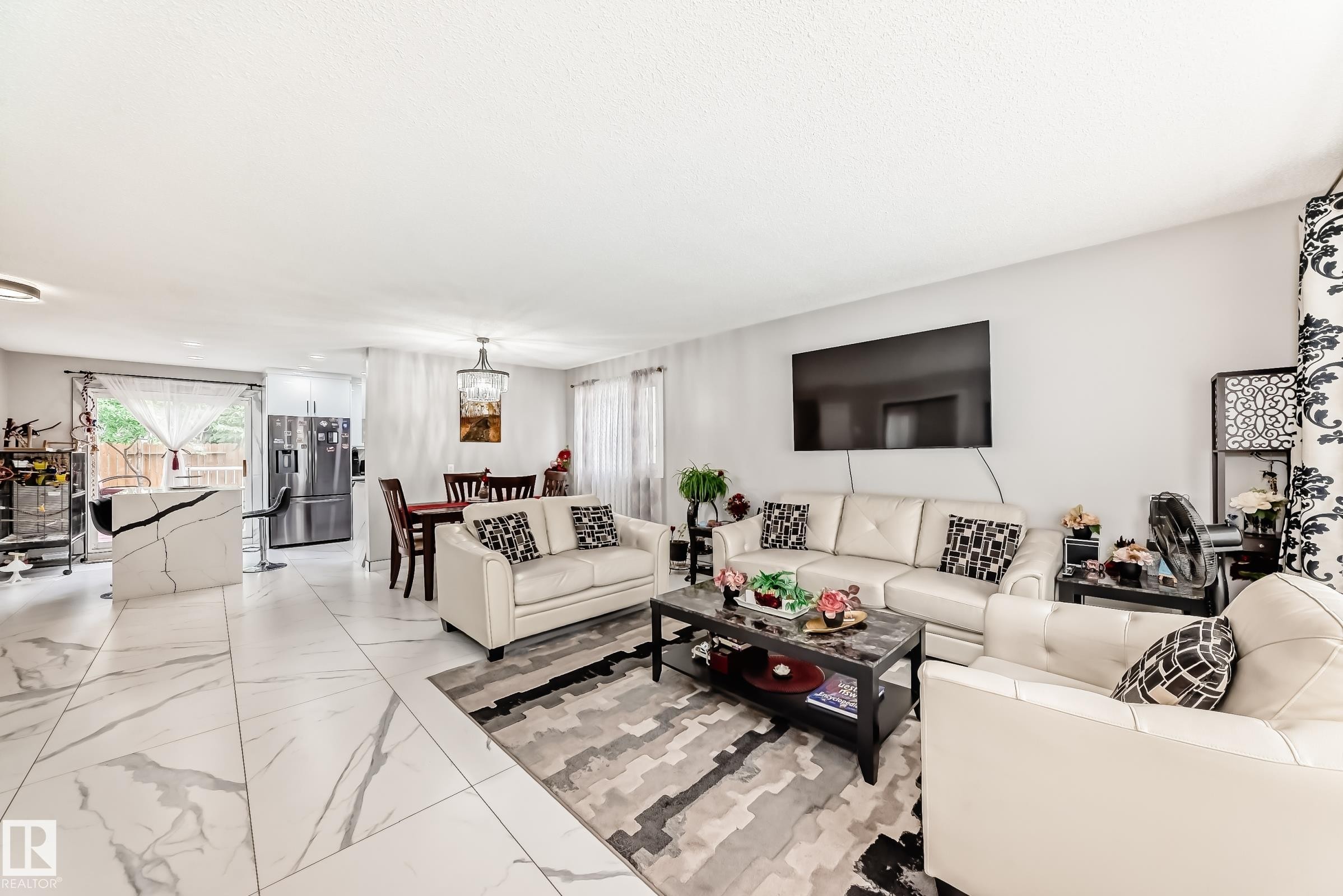 Expansive main living area featuring large format marble-look tile flooring, a white quartz breakfast bar, and recessed lighting - 3843 47 Street Nw, Edmonton, AB - Indoor Photo Showing Living Room