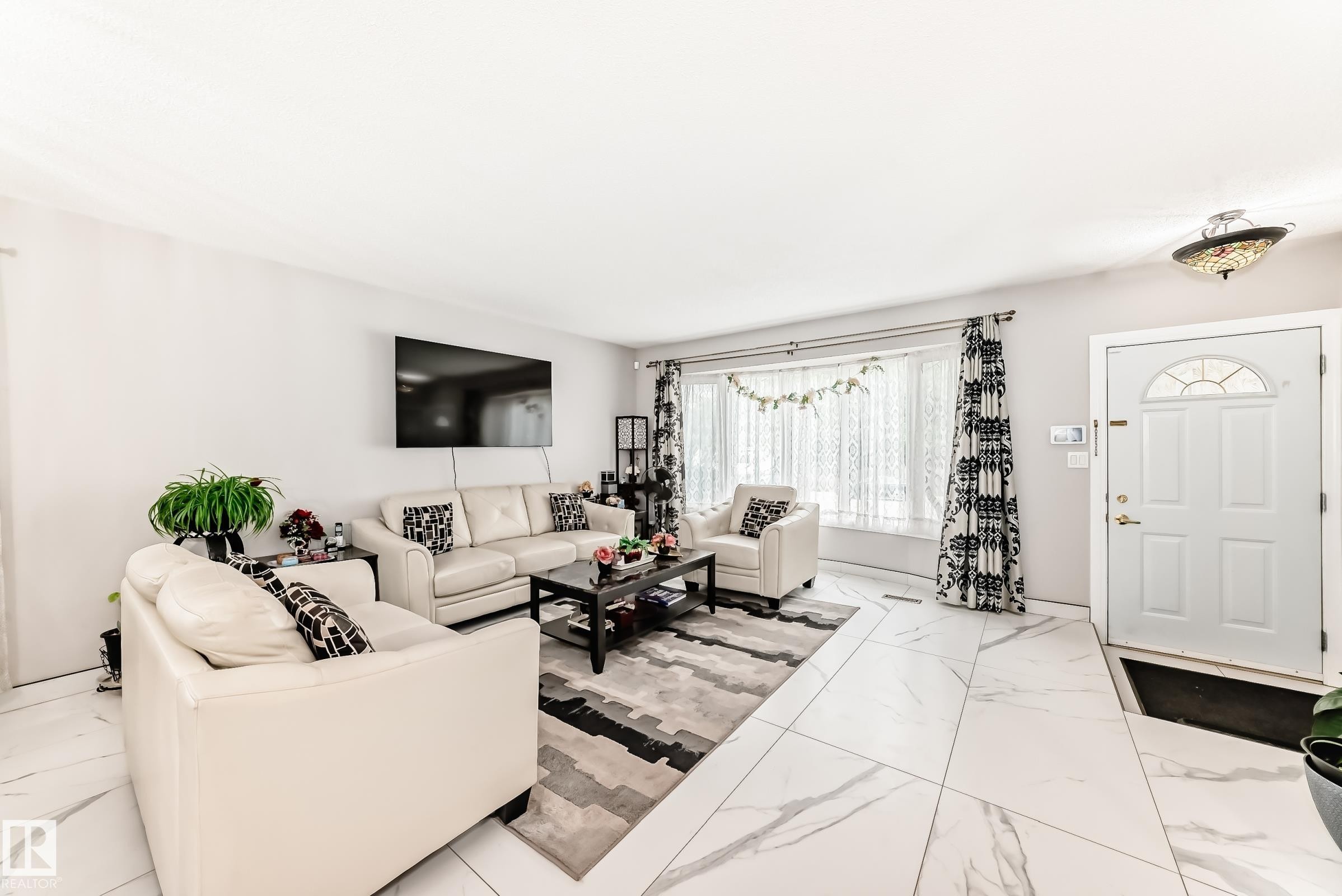 Entry space with white paneled door featuring an arched window insert - 3843 47 Street Nw, Edmonton, AB - Indoor Photo Showing Living Room