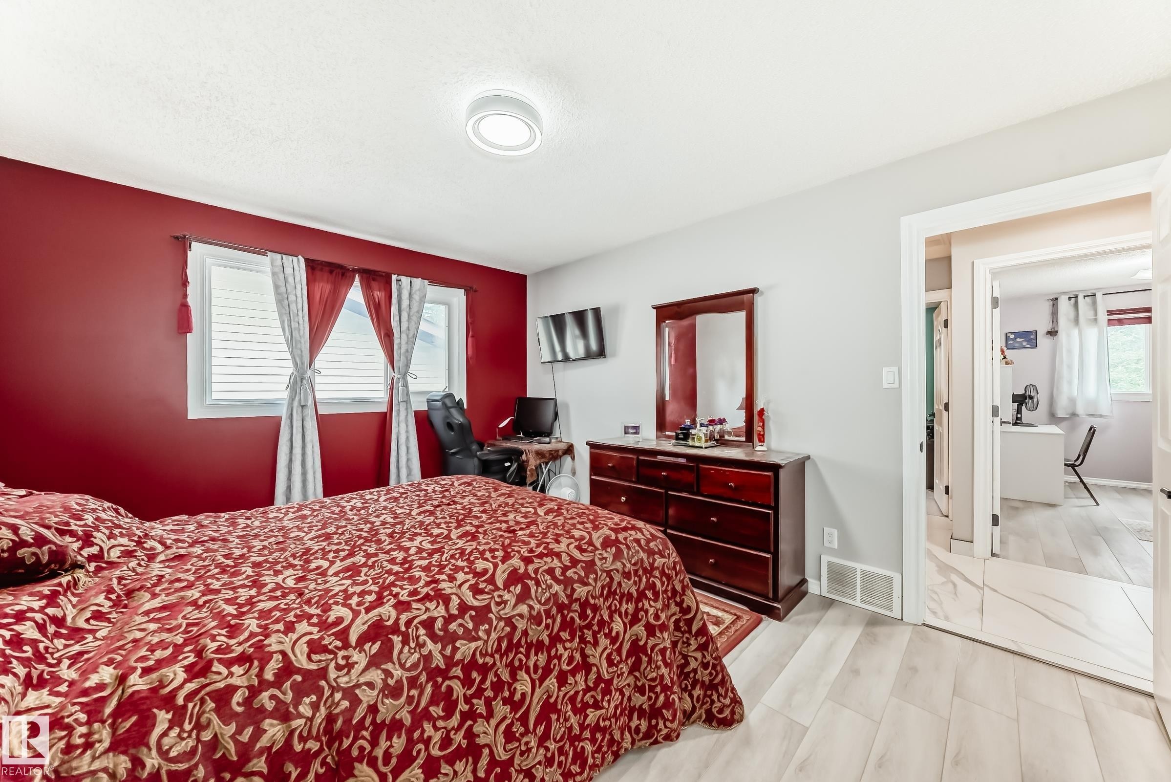 Bedroom featuring light wood-finish flooring, two large windows with blinds, and a flush-mount ceiling light fixture - 3843 47 Street Nw, Edmonton, AB - Indoor Photo Showing Bedroom