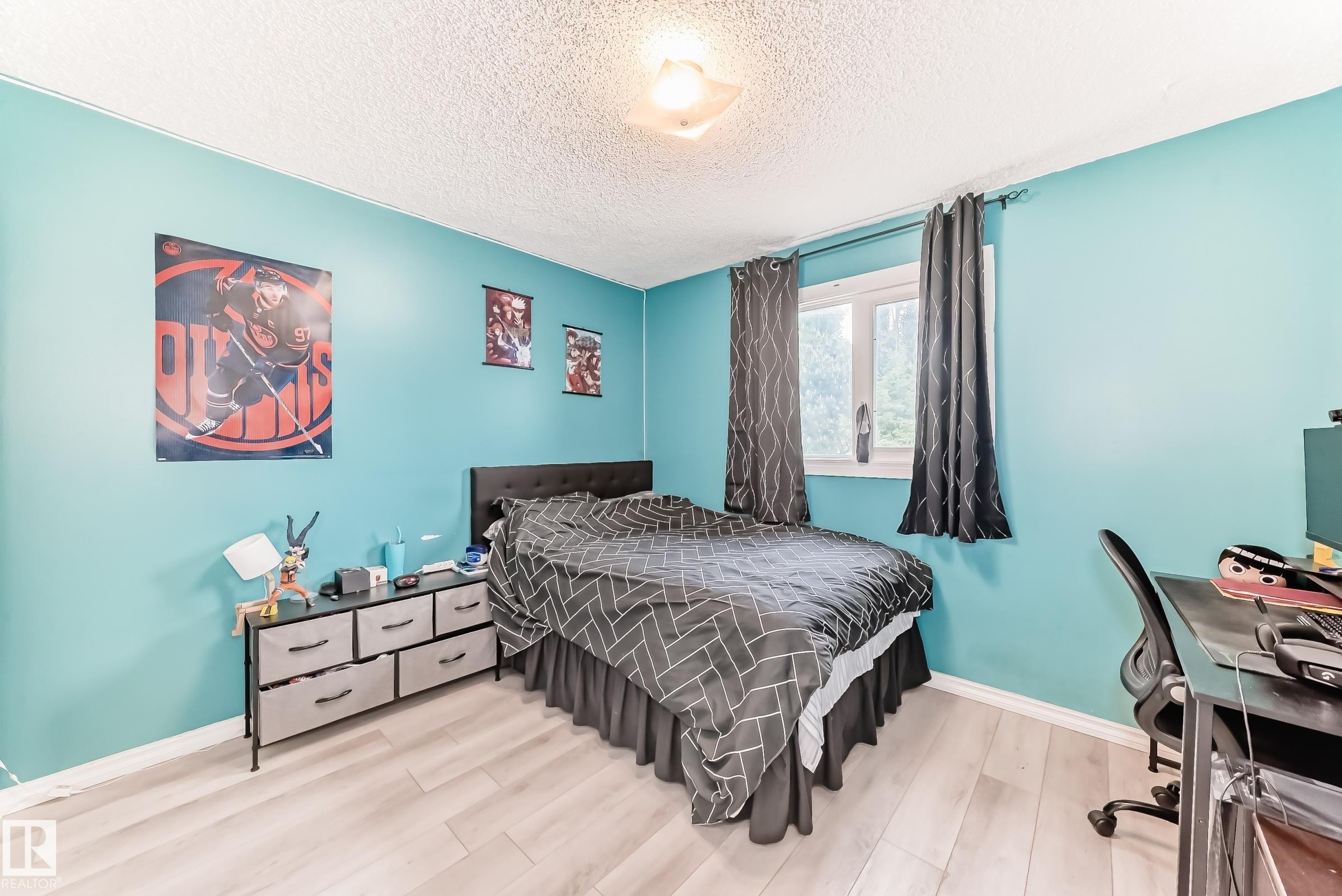 Bedroom featuring light wood-finish flooring, a window with dark drapery, and a textured ceiling - 3843 47 Street Nw, Edmonton, AB - Indoor Photo Showing Bedroom