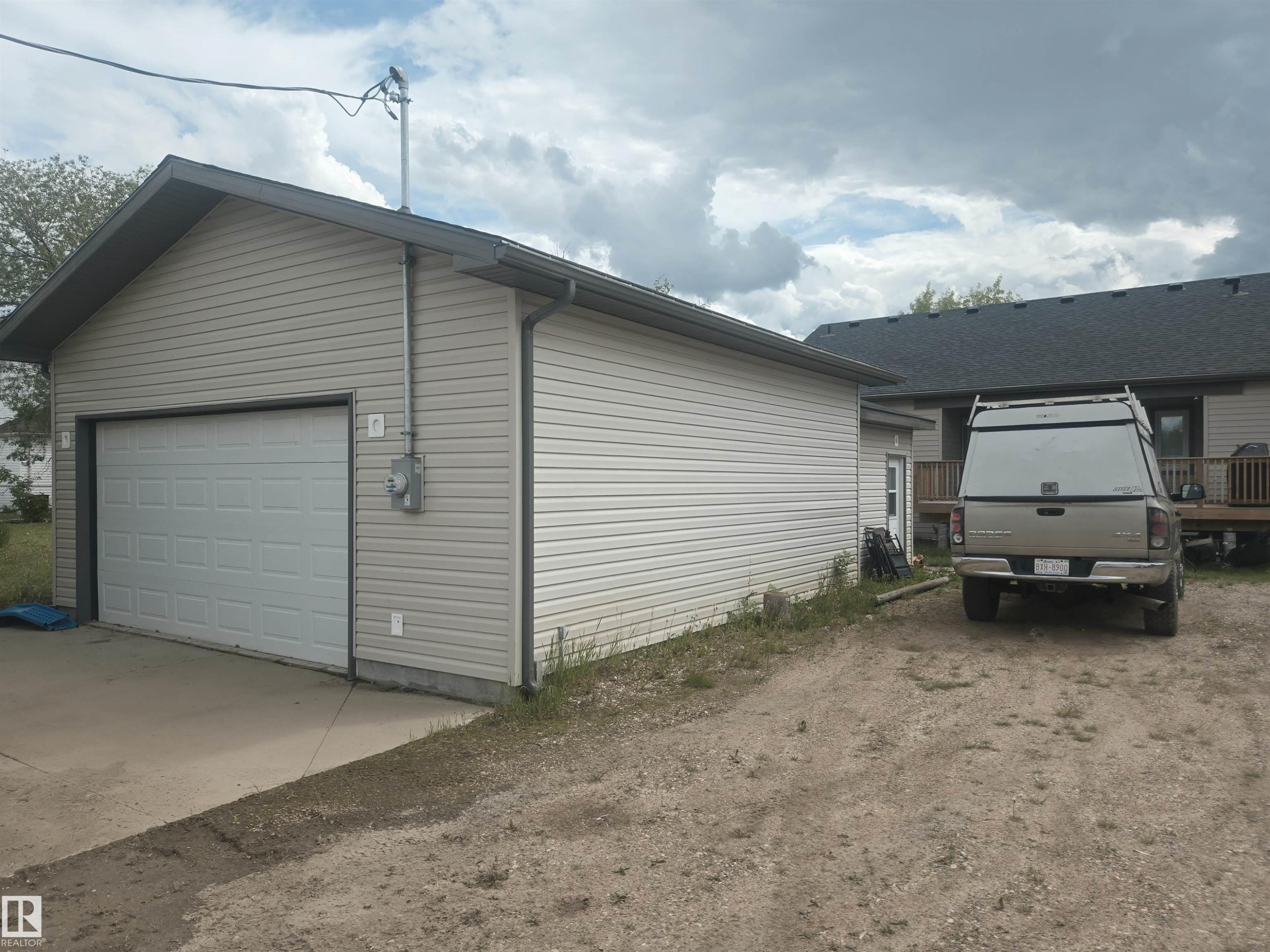 Detached garage featuring light-colored siding and a panel-style garage door - 4808 50 Avenue, Lamont, AB