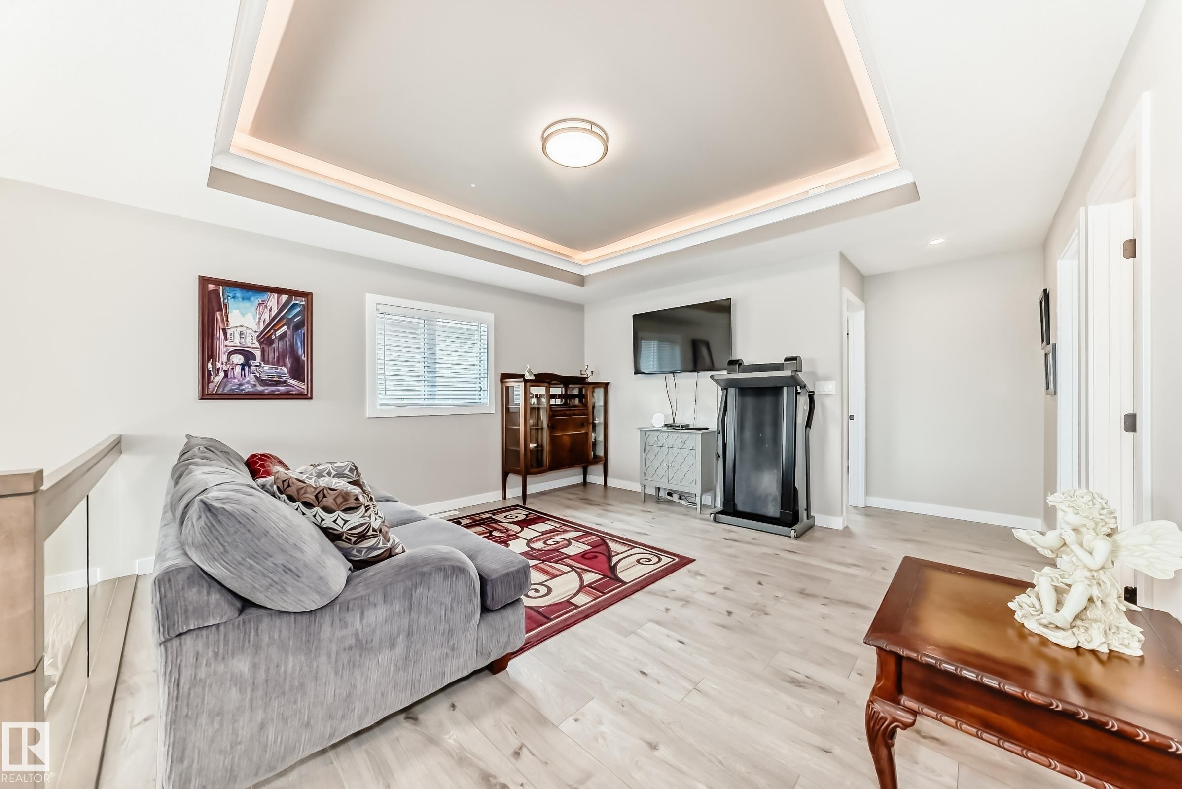 Recessed tray ceiling with perimeter lighting, light wood-finish flooring, and light neutral wall paint - 3895 Robins Crescent Nw, Edmonton, AB - Indoor