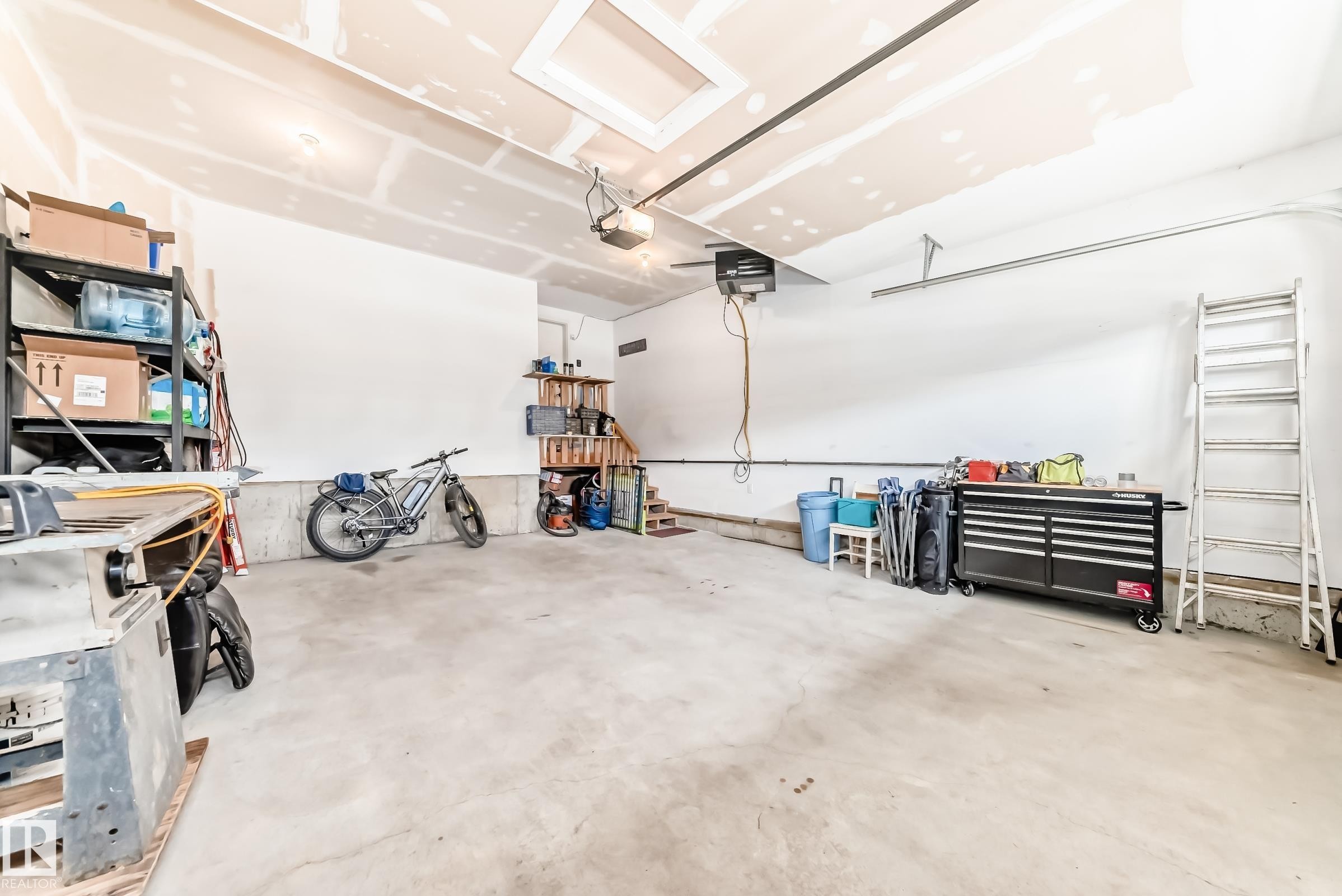 Spacious garage featuring a concrete floor, white walls, and an automatic garage door opener - 3895 Robins Crescent Nw, Edmonton, AB - Indoor Photo Showing Garage