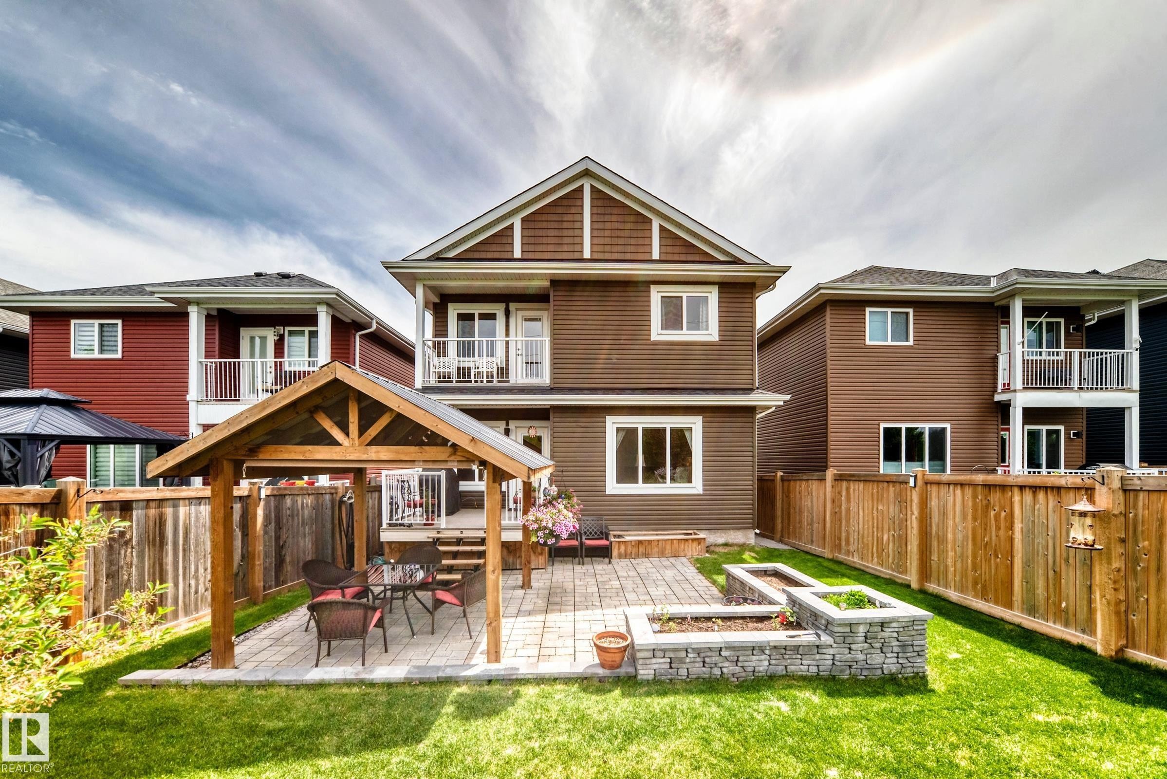 Backyard featuring a wooden gazebo with a paved patio, stone-faced raised garden beds, and a full privacy fence - 3895 Robins Crescent Nw, Edmonton, AB - Outdoor