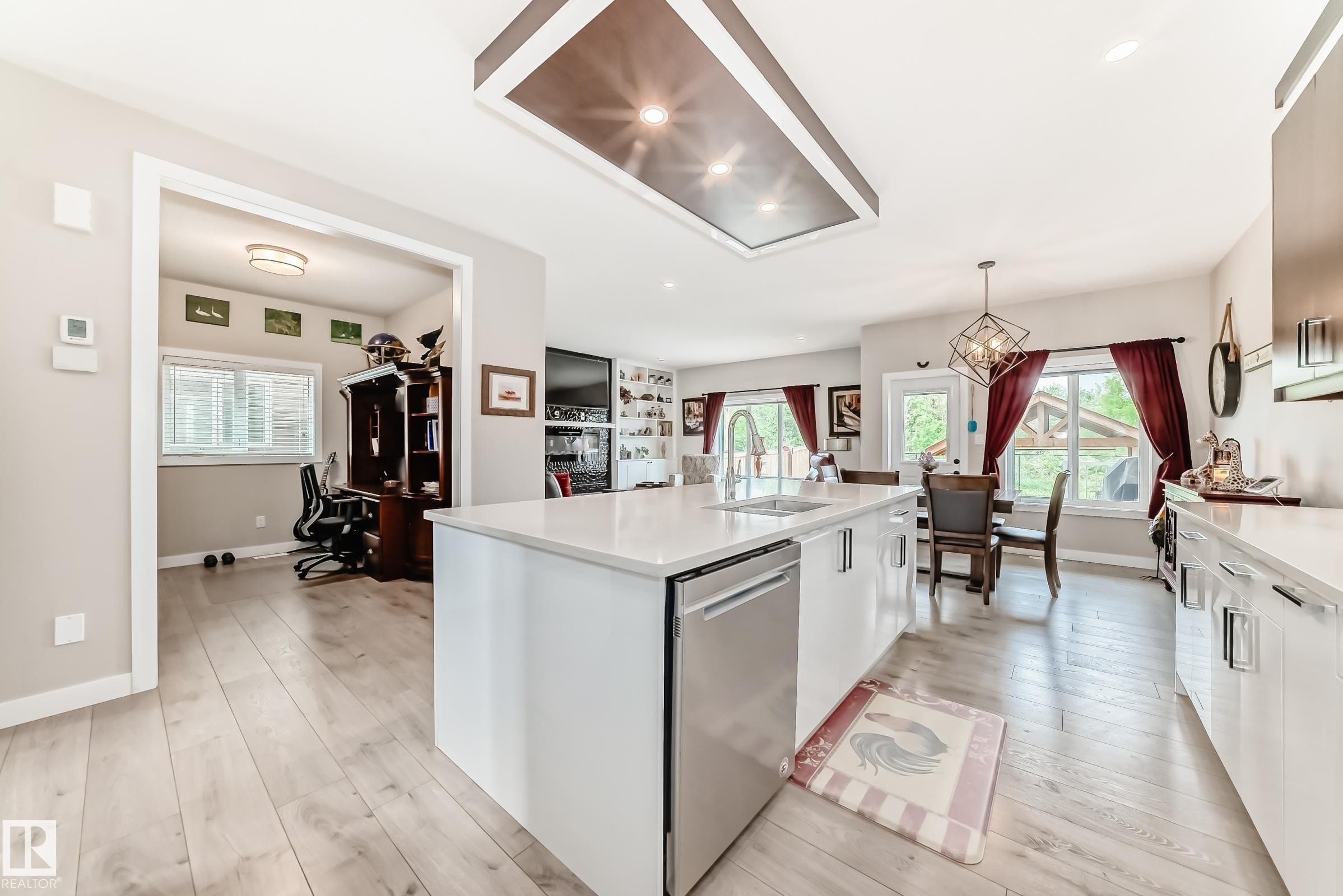 Contemporary kitchen featuring a large center island with integrated sink, stainless steel dishwasher, and light-toned countertops - 3895 Robins Crescent Nw, Edmonton, AB - Indoor Photo Showing Kitchen