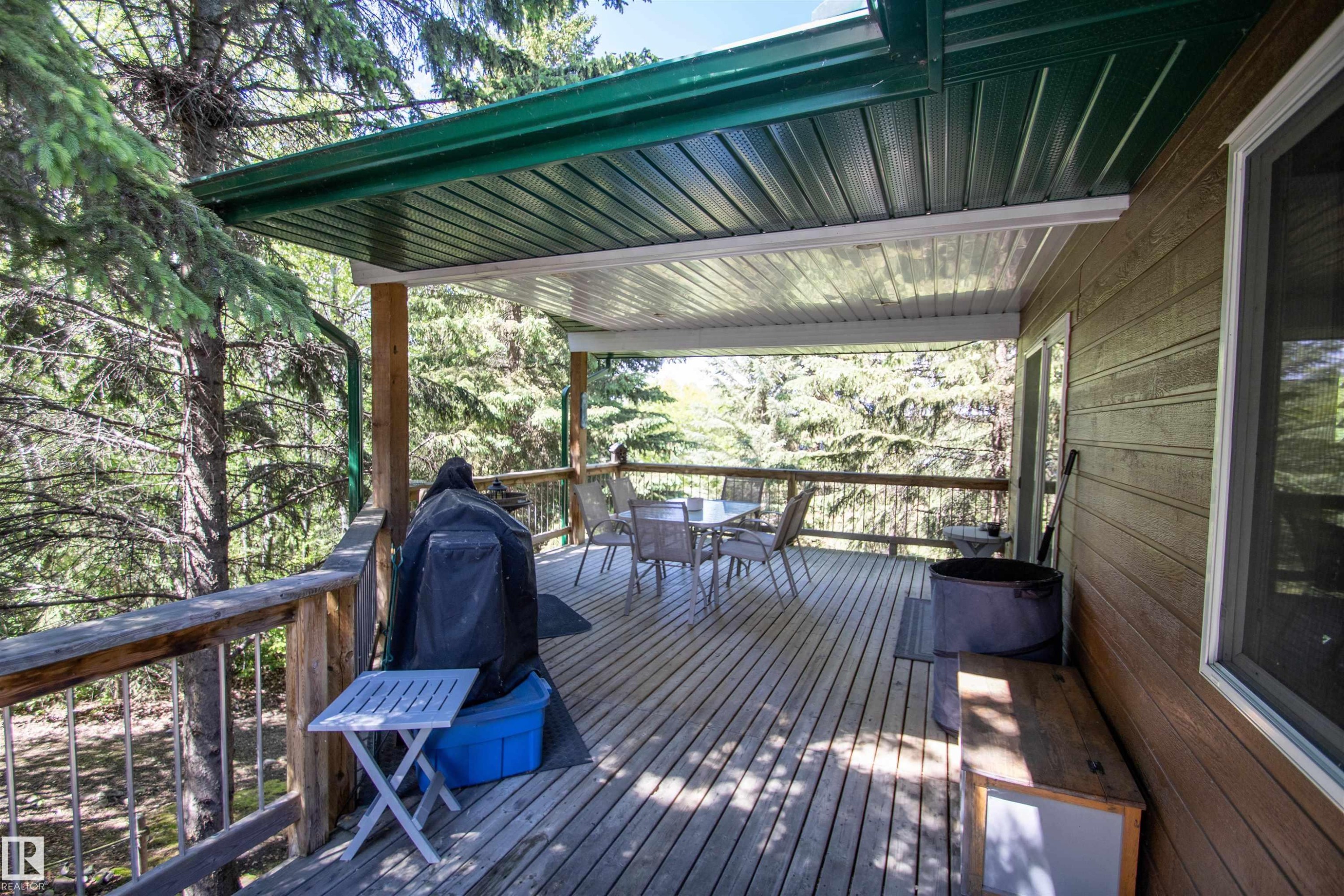 Covered wood deck with slatted wood railing and a green metal awning - 104 60201 Rng Rd 122, Rural St. Paul County, AB