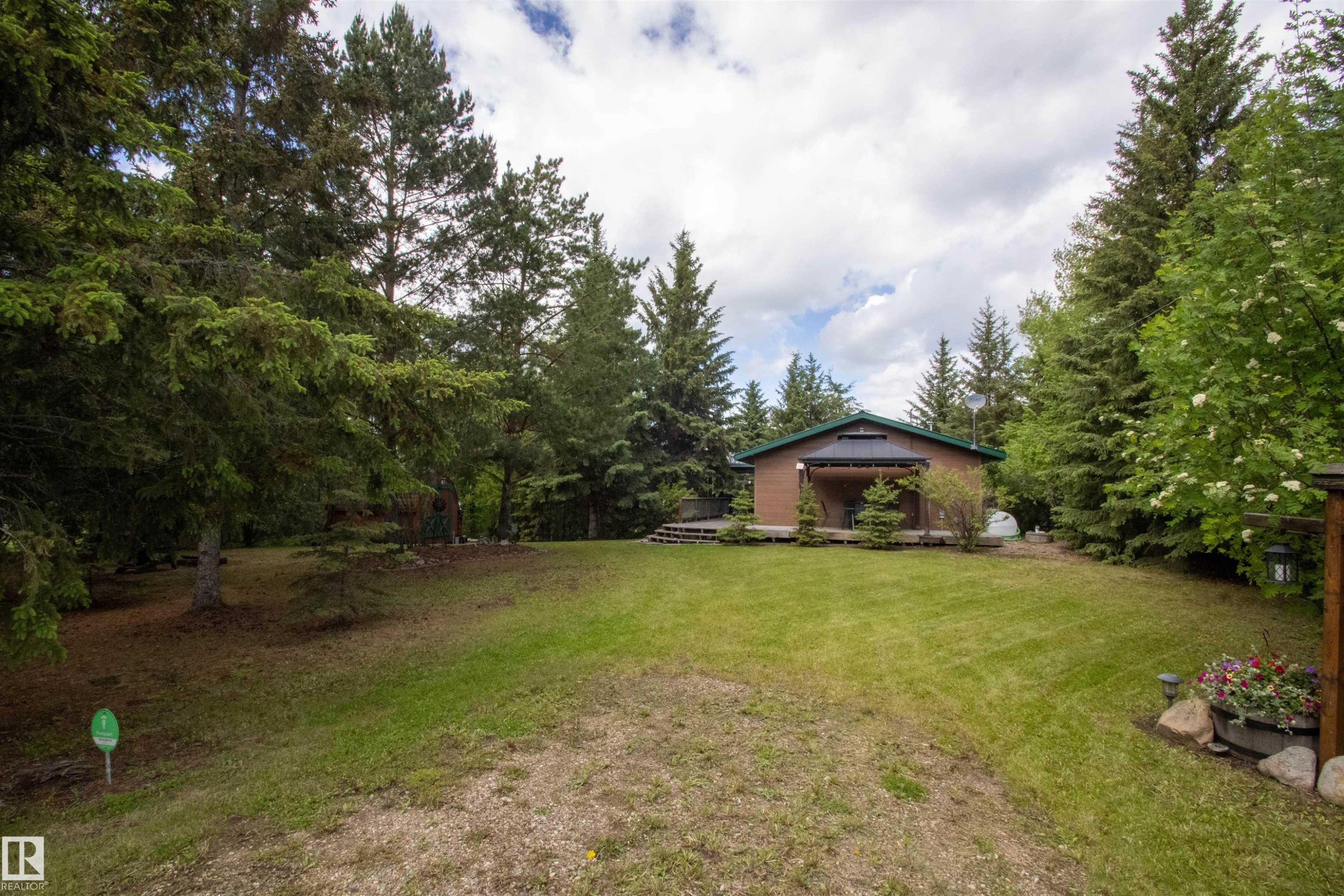 Lush green lawn surrounding a brown-sided house with a dark green roof - 104 60201 Rng Rd 122, Rural St. Paul County, AB