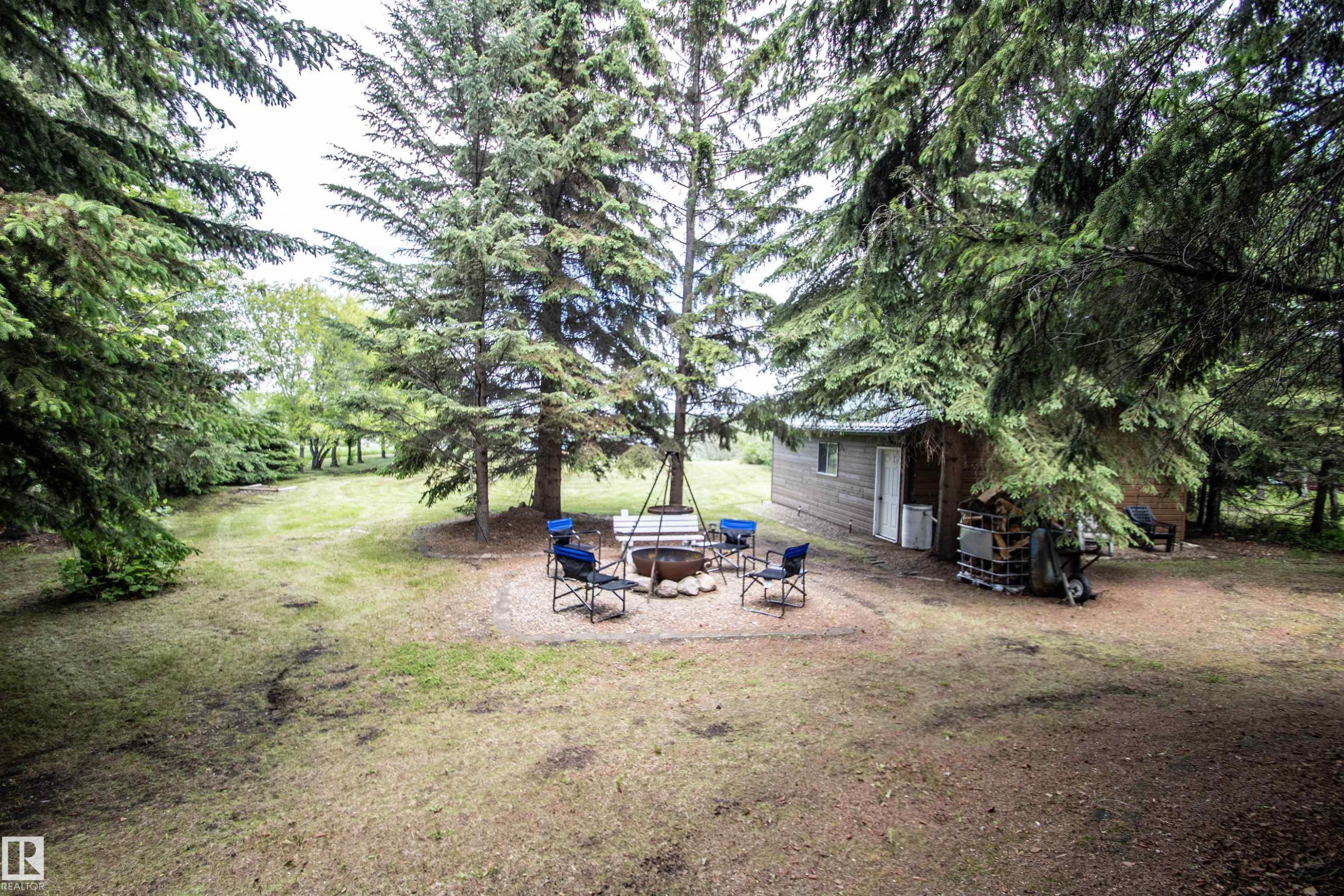 Exterior building with wood siding and a metal roof, surrounded by mature evergreen trees - 104 60201 Rng Rd 122, Rural St. Paul County, AB