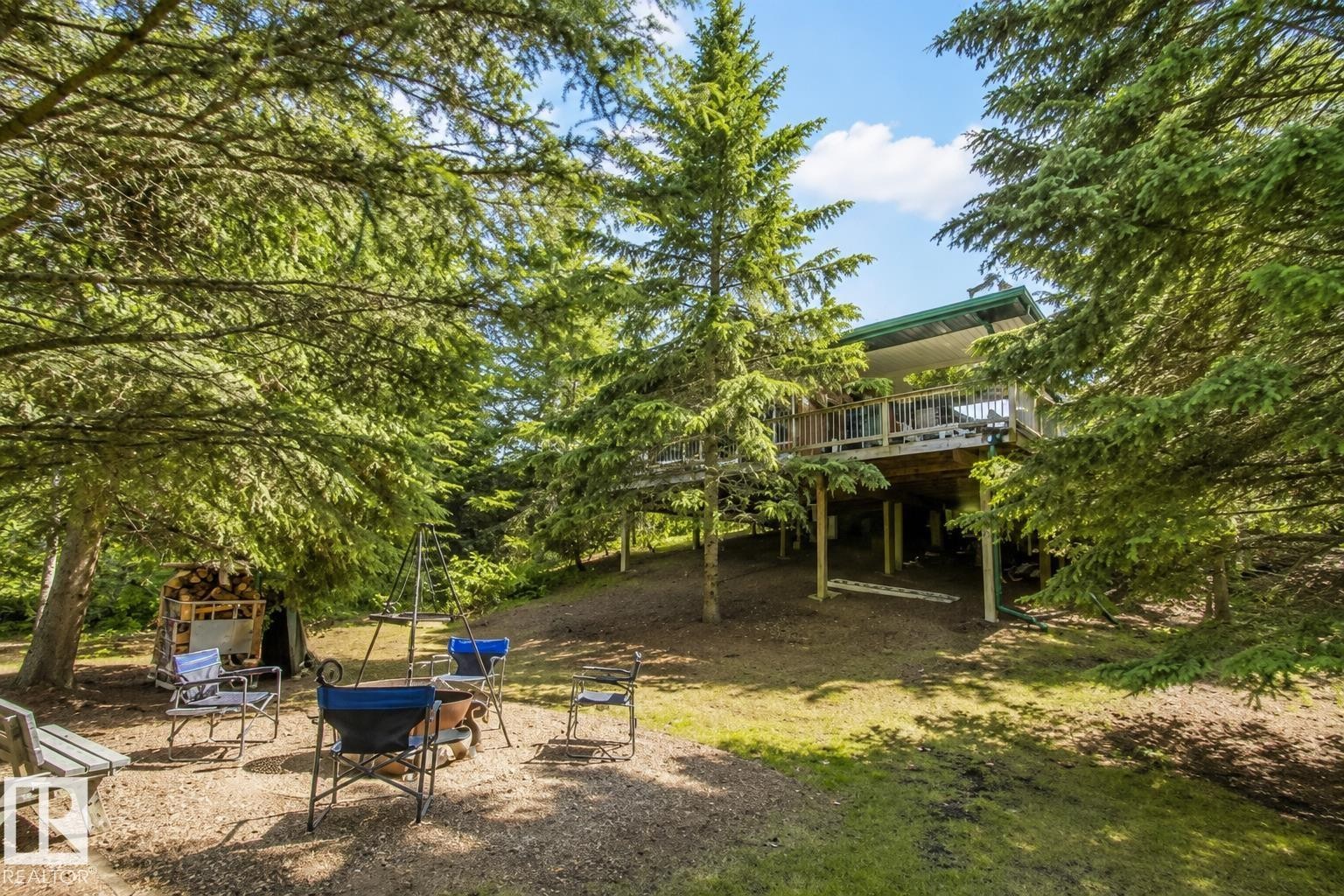 Elevated exterior deck with wood railings and a green roofline, surrounded by mature evergreen trees - 104 60201 Rng Rd 122, Rural St. Paul County, AB