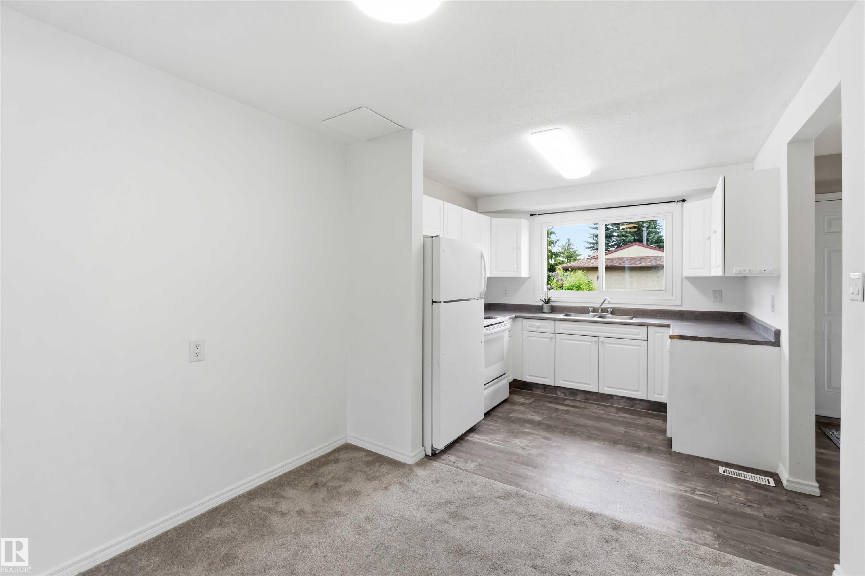 Kitchen area featuring white cabinetry, a single basin sink, and dark countertops - 17325 85 Avenue Nw, Edmonton, AB