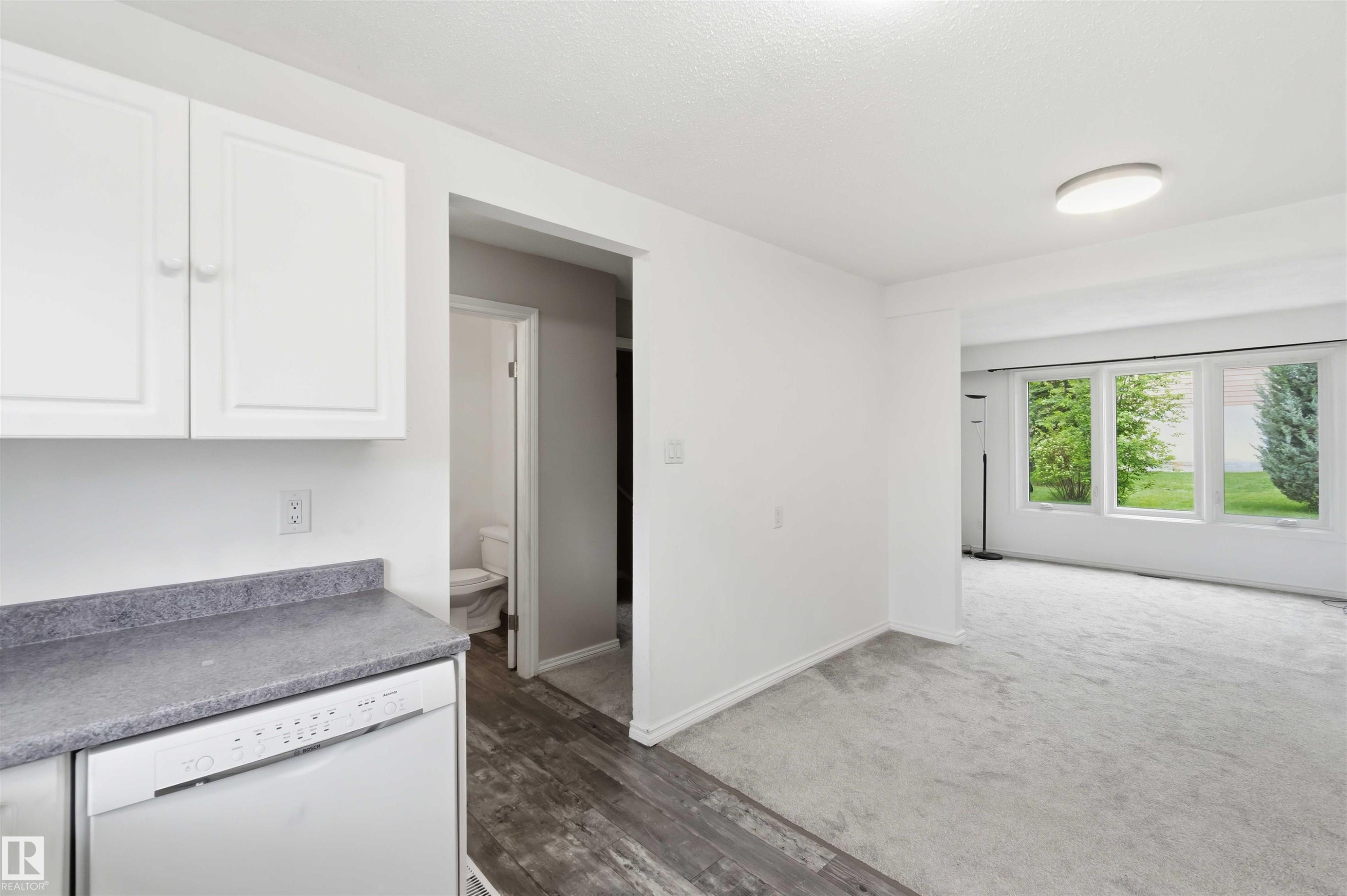 Kitchen area featuring white cabinetry, a white dishwasher, and gray countertop - 17325 85 Avenue Nw, Edmonton, AB