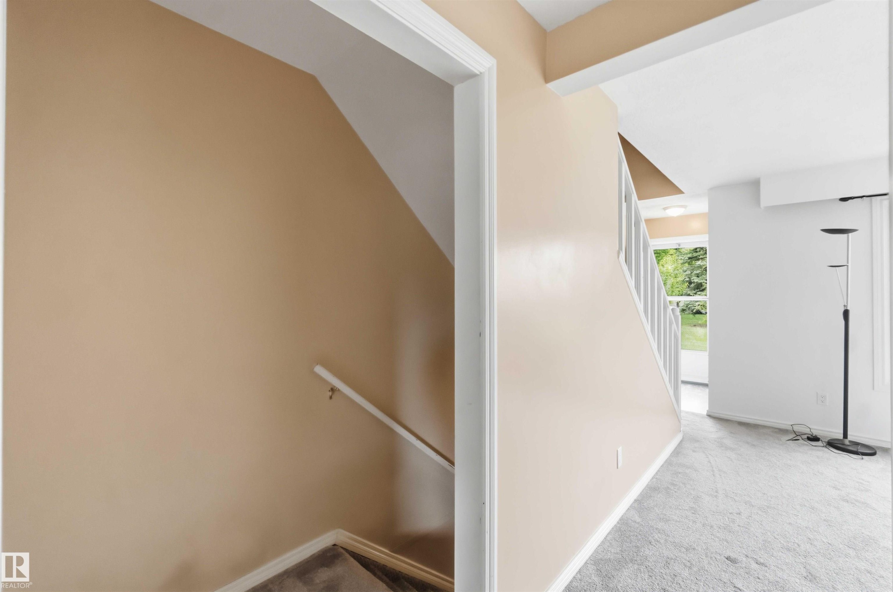 Interior stairway with painted walls, white trim, and light grey carpet - 17325 85 Avenue Nw, Edmonton, AB